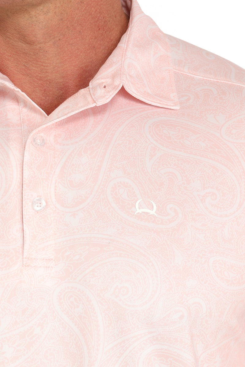 Close-up of a man wearing a light pink collared shirt with a subtle paisley pattern