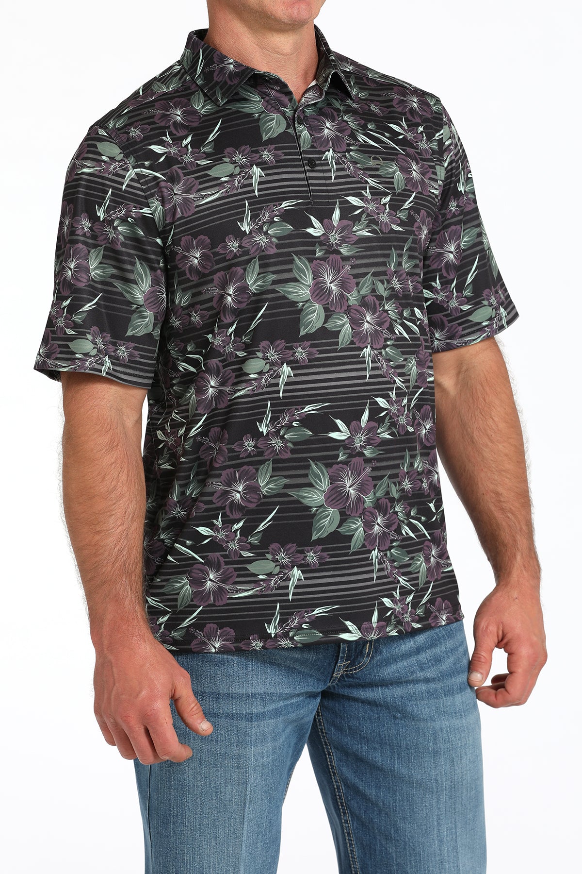 Man wearing a black floral patterned shirt and blue jeans on a white background