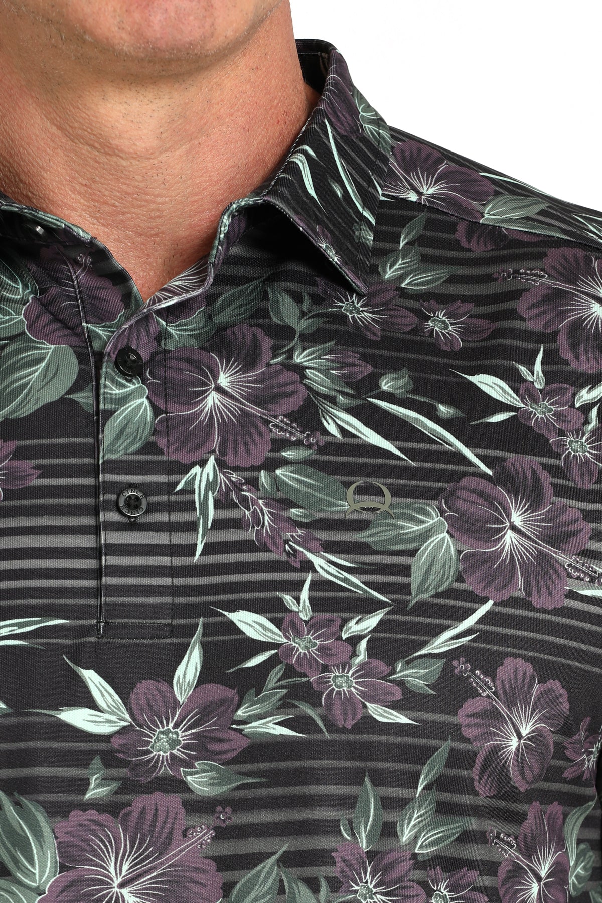 Close-up of a dark floral patterned shirt with green and purple flowers on a black background.