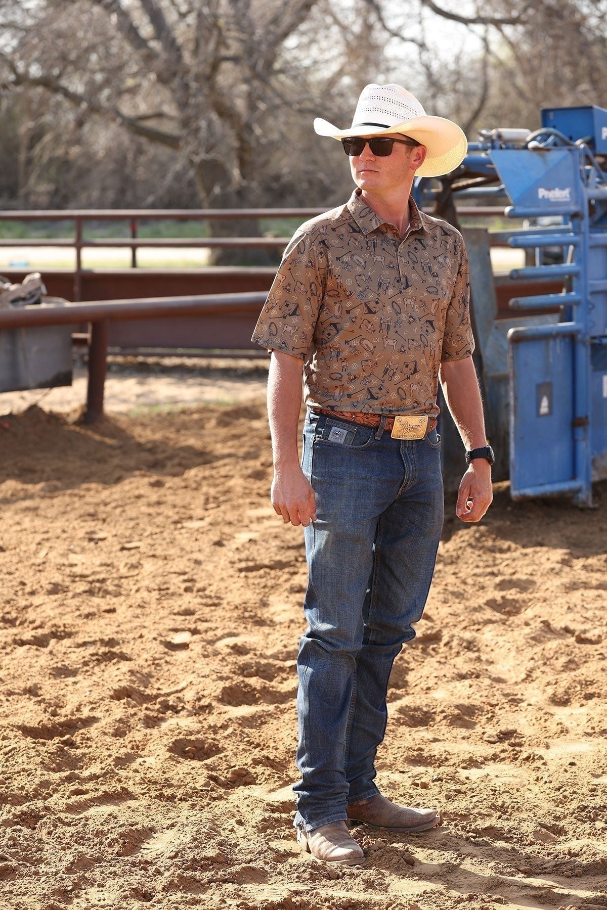 Go West Supply men's brown short sleeve polo with all-over cowboy motif print, ArenaFlex fabric.