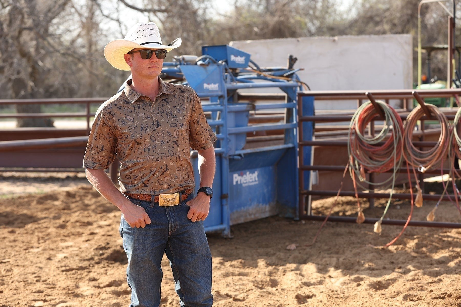 Go West Supply men's brown ArenaFlex polo with all-over cowboy motif print, short sleeves, and classic collar.