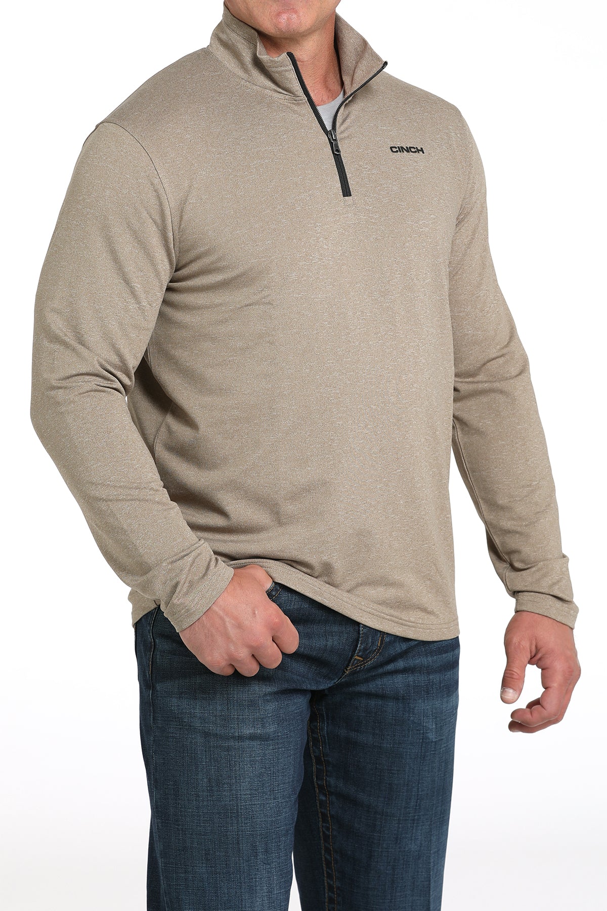 Man wearing a beige long-sleeve shirt with a quarter zip and jeans on a white background