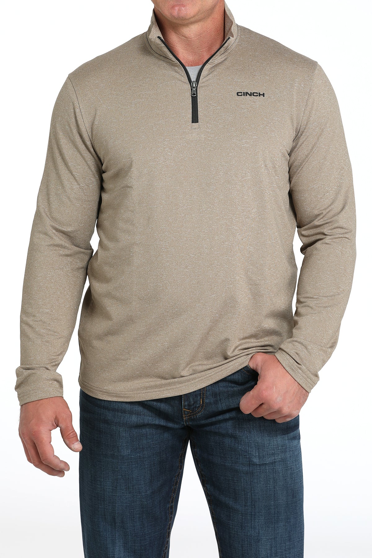 Man wearing a beige long-sleeve shirt with a quarter zip and blue jeans on a white background