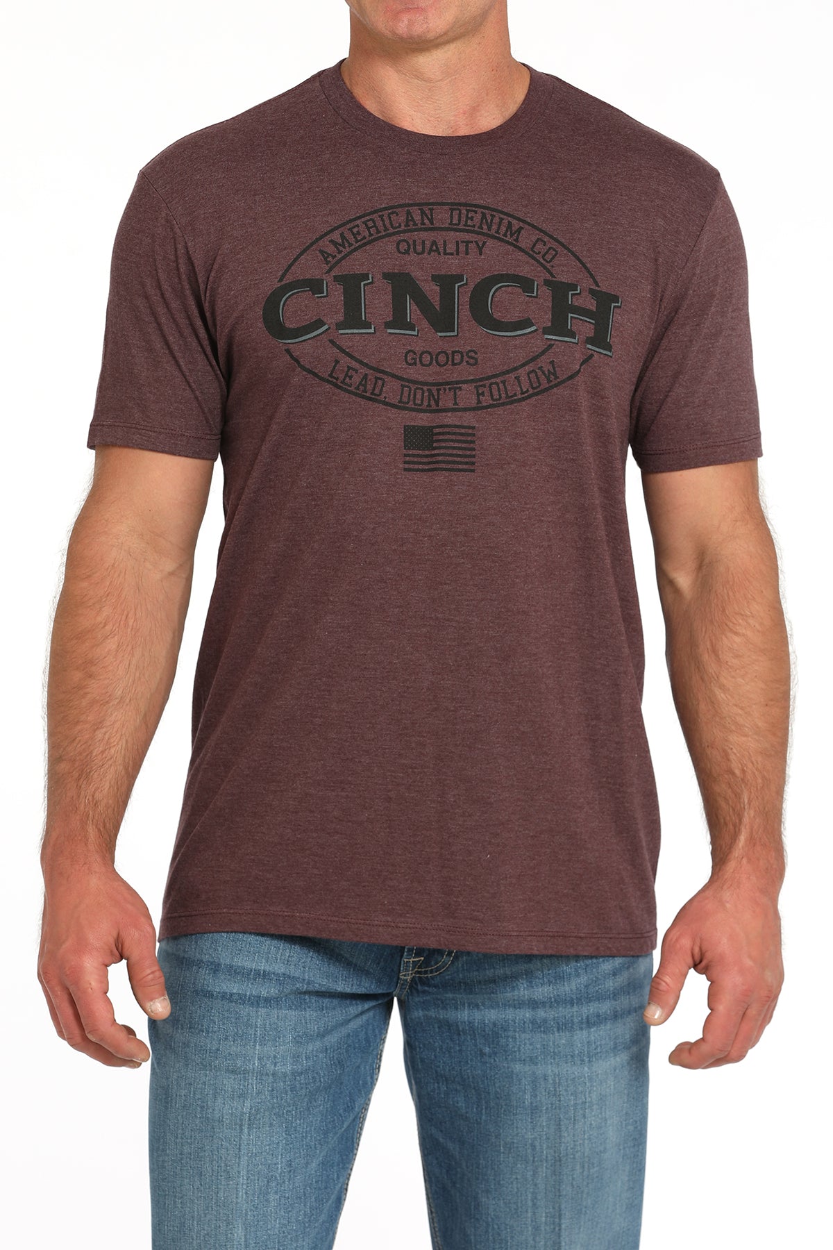 Man wearing a brown t-shirt with a large 'Cinch' graphic on the front and blue jeans on a white background