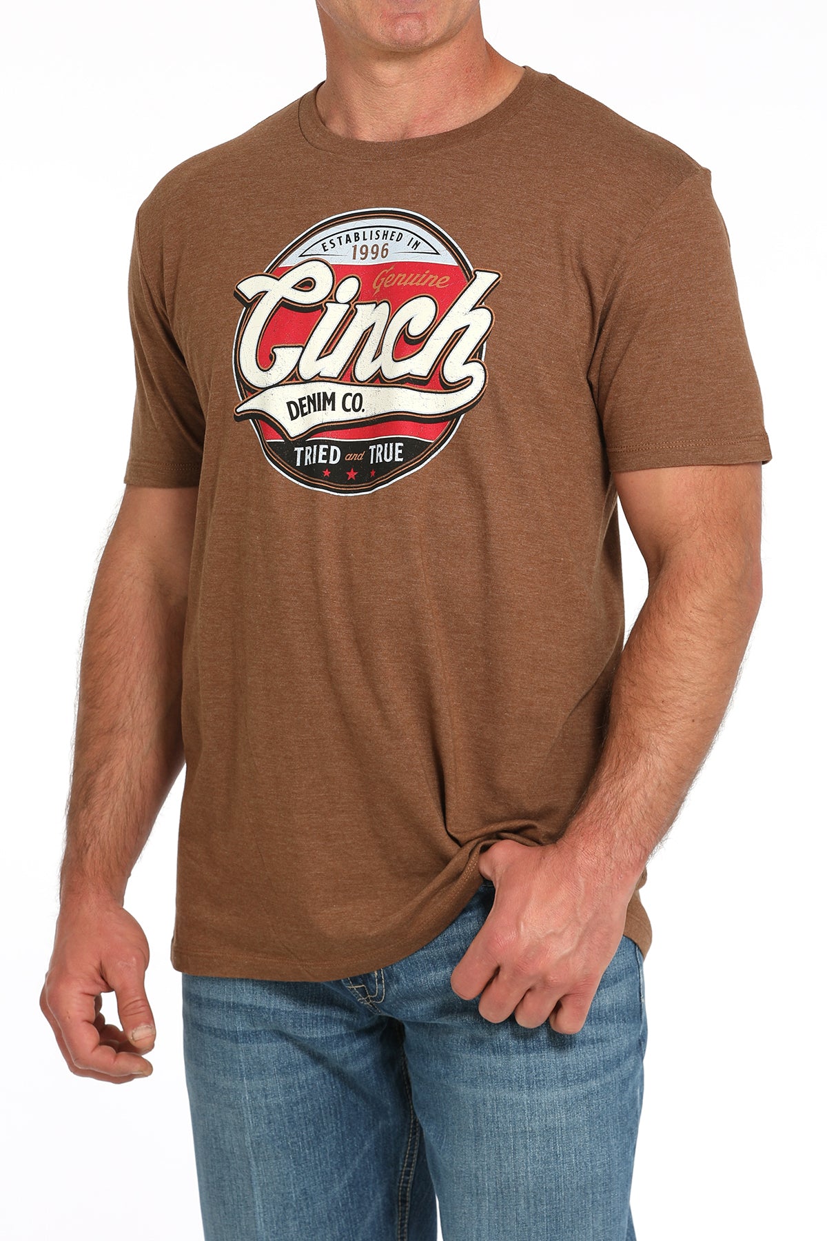 Man wearing a brown t-shirt with a large 'Cinch' graphic on the front and blue jeans on a white background