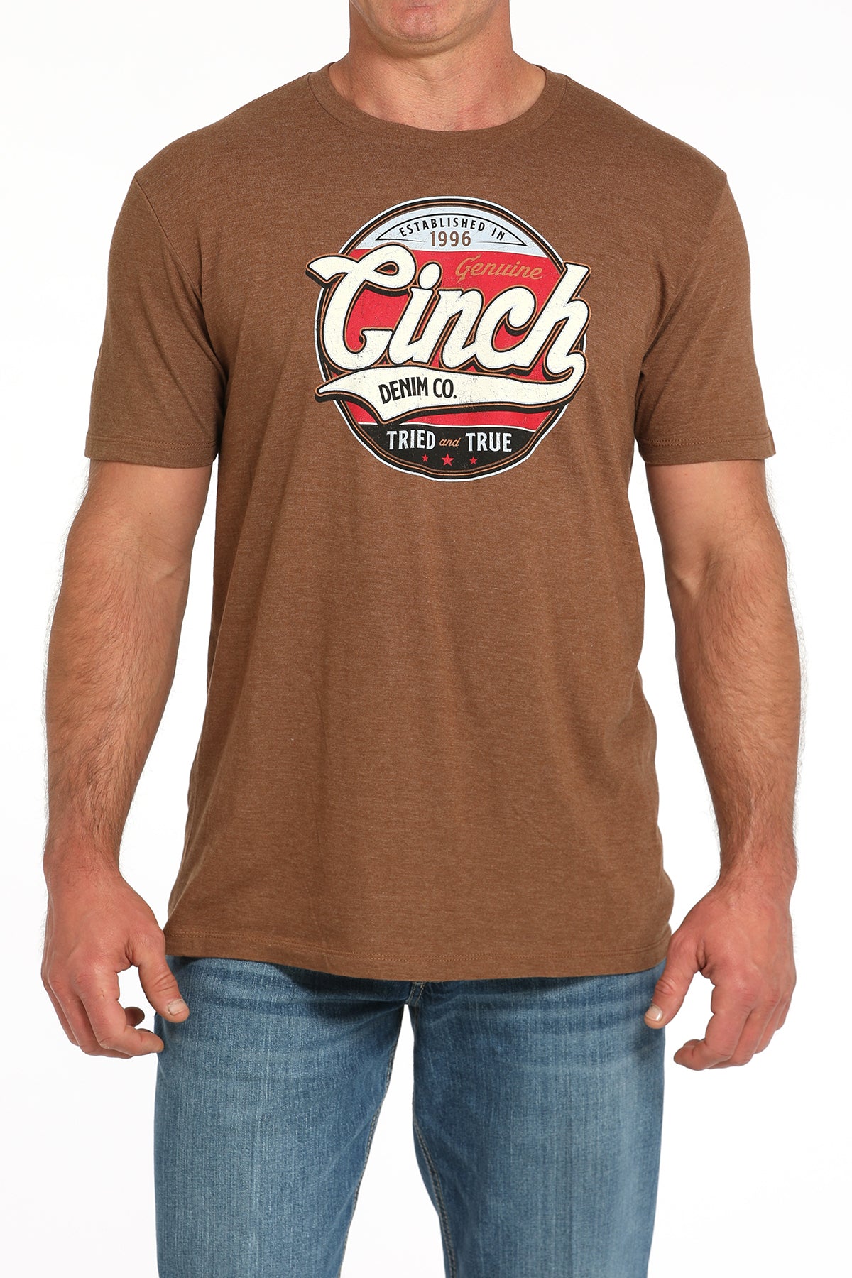 Man wearing a brown t-shirt with a large 'Cinch' graphic on the front and blue jeans on a white background