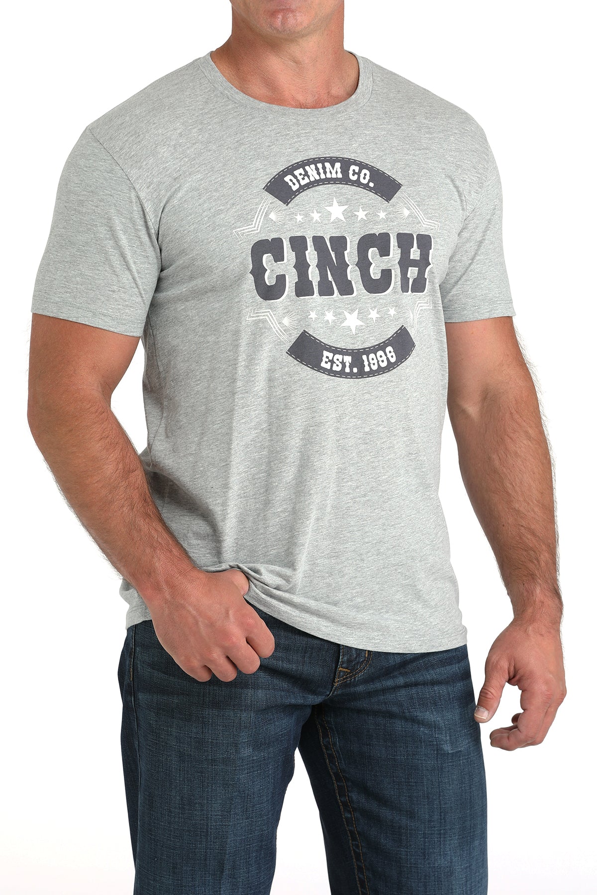 Man wearing a light gray t-shirt with a large 'Cinch' graphic on the front and blue jeans on a white background