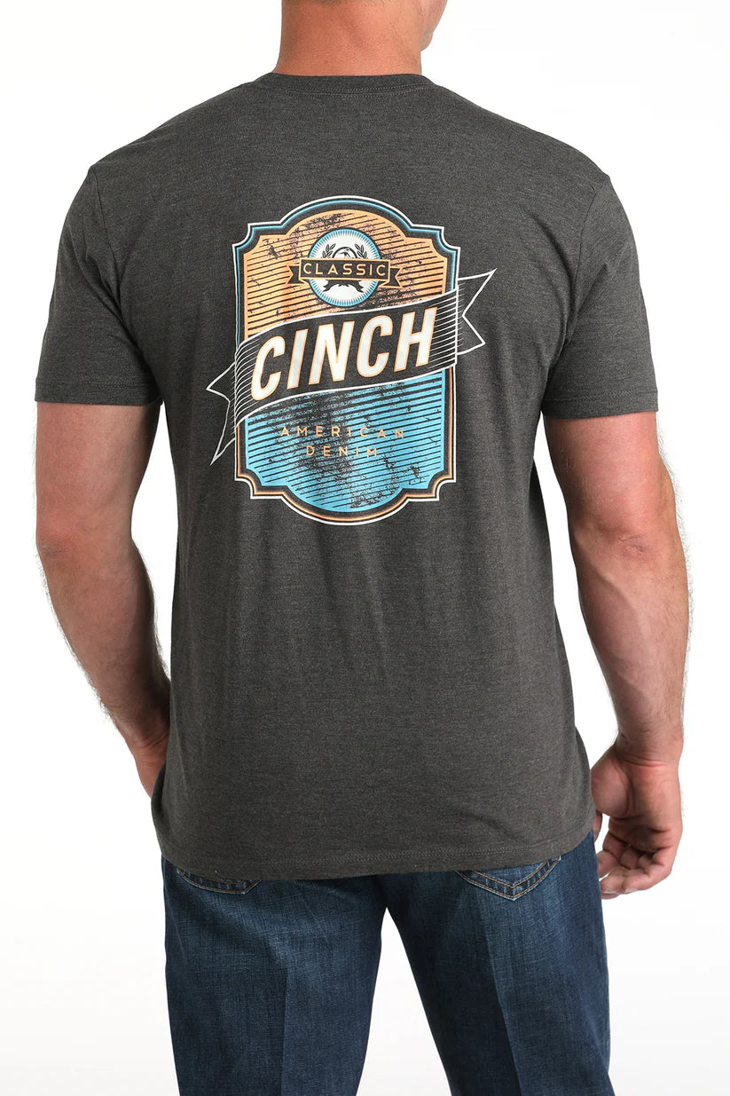 Back view of a charcoal short sleeve Cinch t-shirt featuring a large multicolor western-inspired back graphic, paired with jeans
