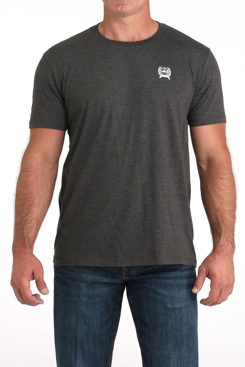 Man wearing a charcoal short sleeve Cinch t-shirt with small chest logo and jeans on a white background