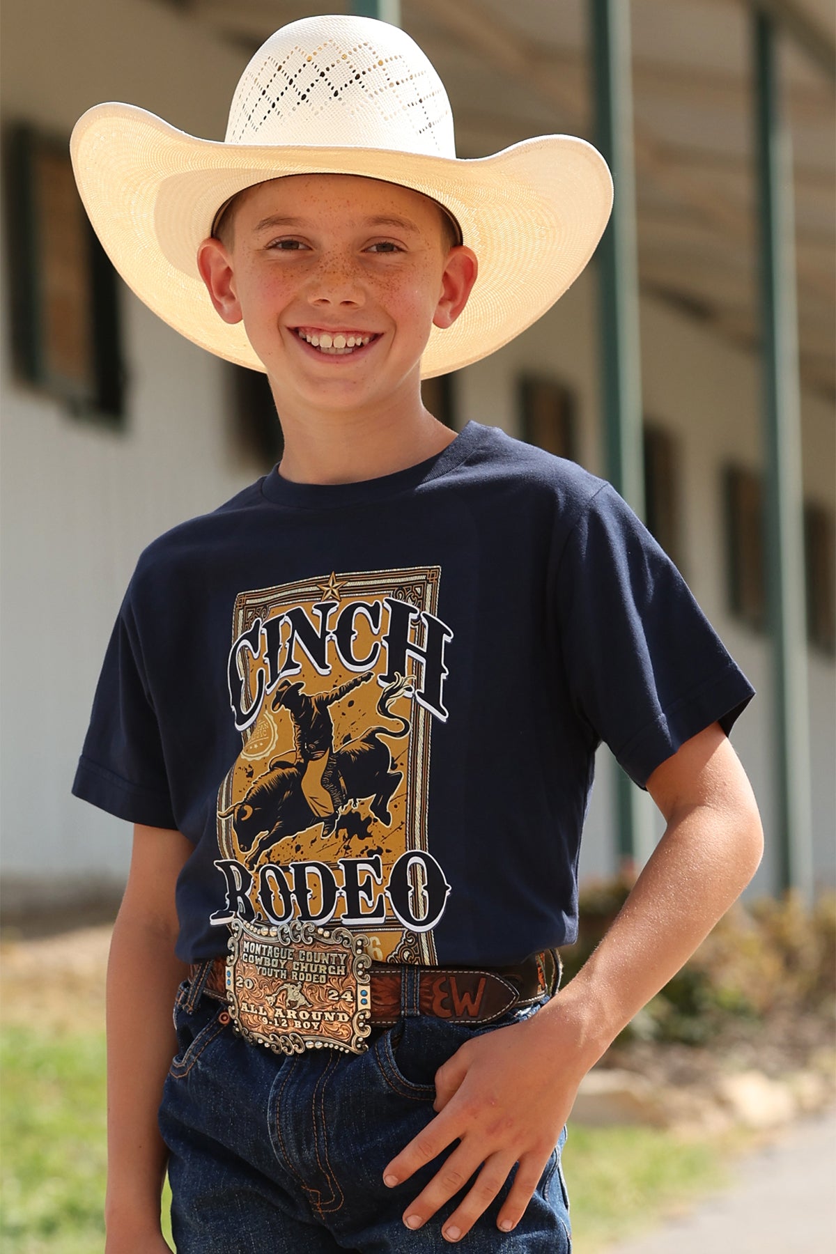 Young boy wearing a cowboy hat and navy t-shirt with a CINCH rodeo graphic.