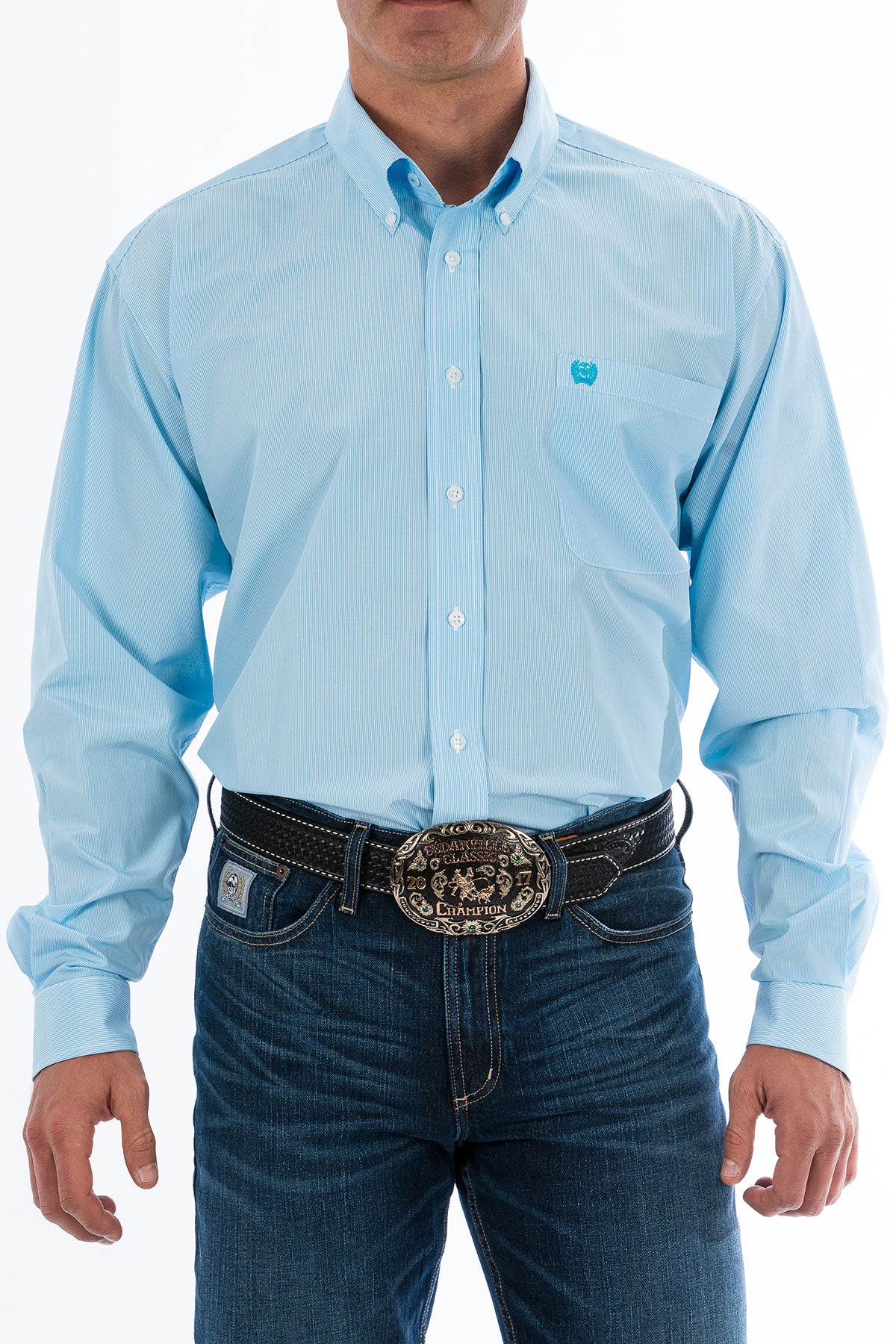 Man wearing a light blue, long sleeve, button-down shirt, with jeans and a western belt