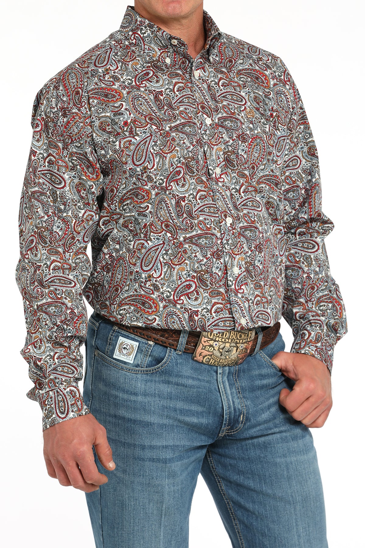 Man wearing a long sleeve button-down shirt with an all-over paisley pattern, paired with jeans and a belt