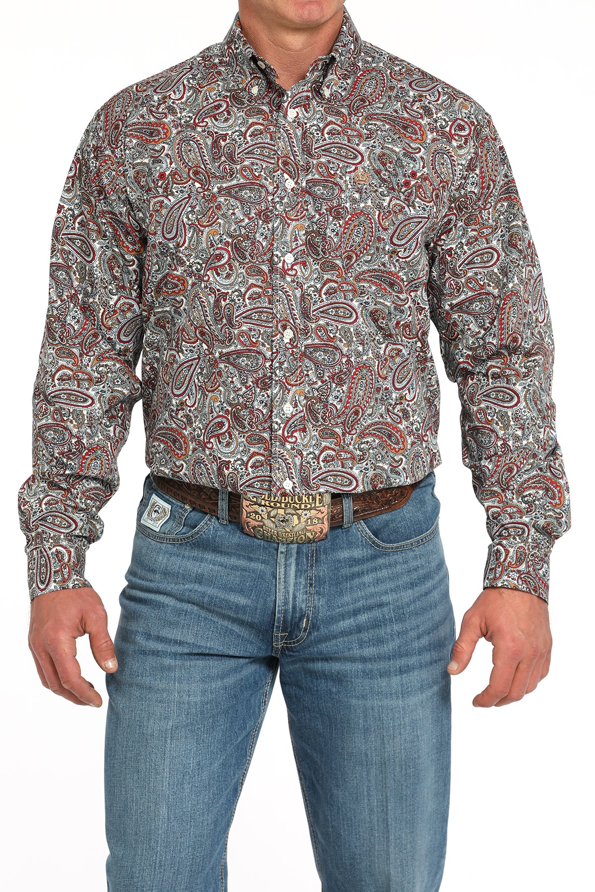 Man wearing a long sleeve button-down shirt with an all-over paisley pattern, paired with jeans and a belt