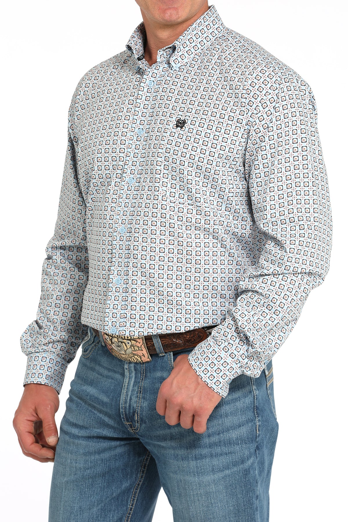 Man wearing a patterned long sleeve button-down shirt with jeans and a belt