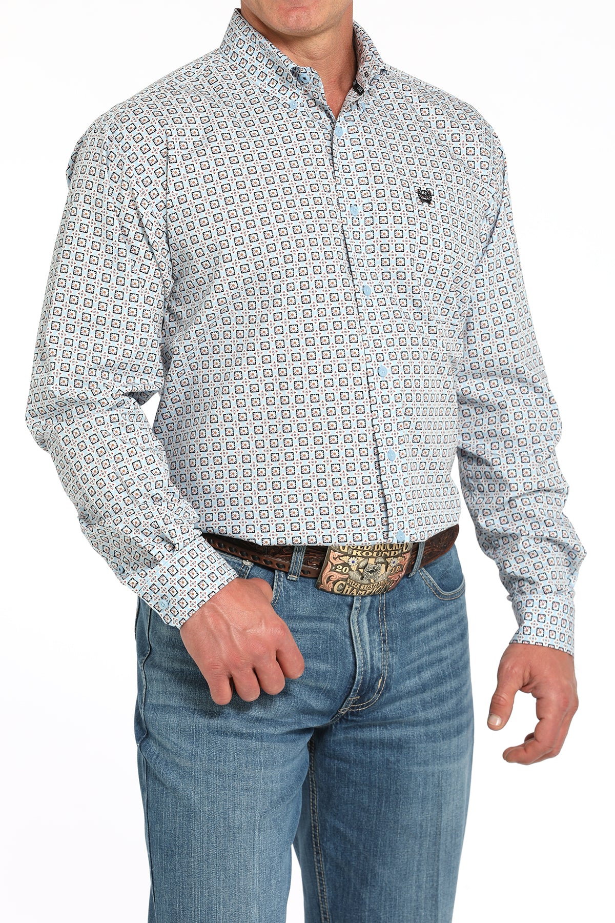 Man wearing a patterned long sleeve button-down shirt with jeans and a belt