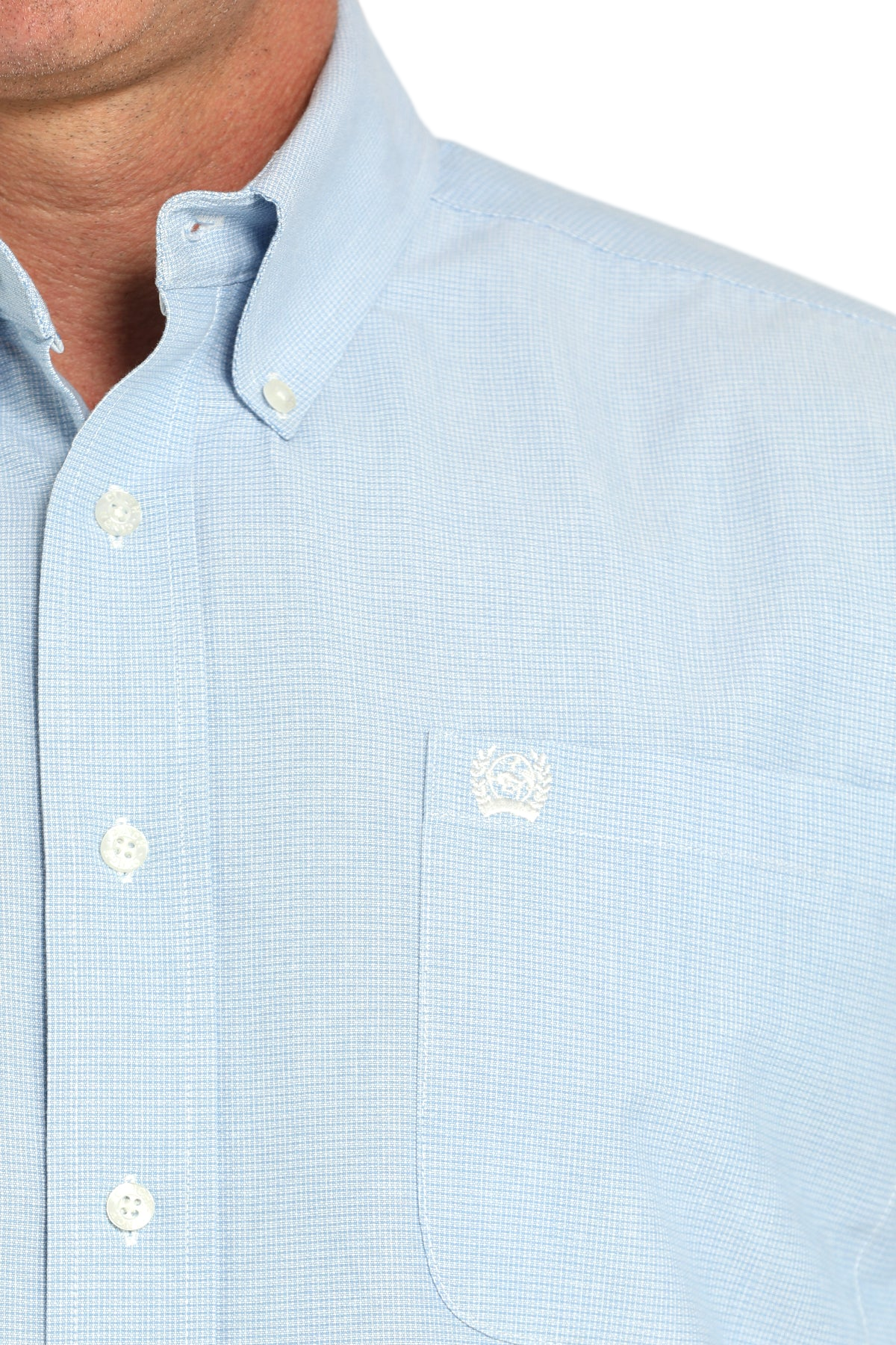 Close-up of a man wearing a light blue button-up shirt on a white background