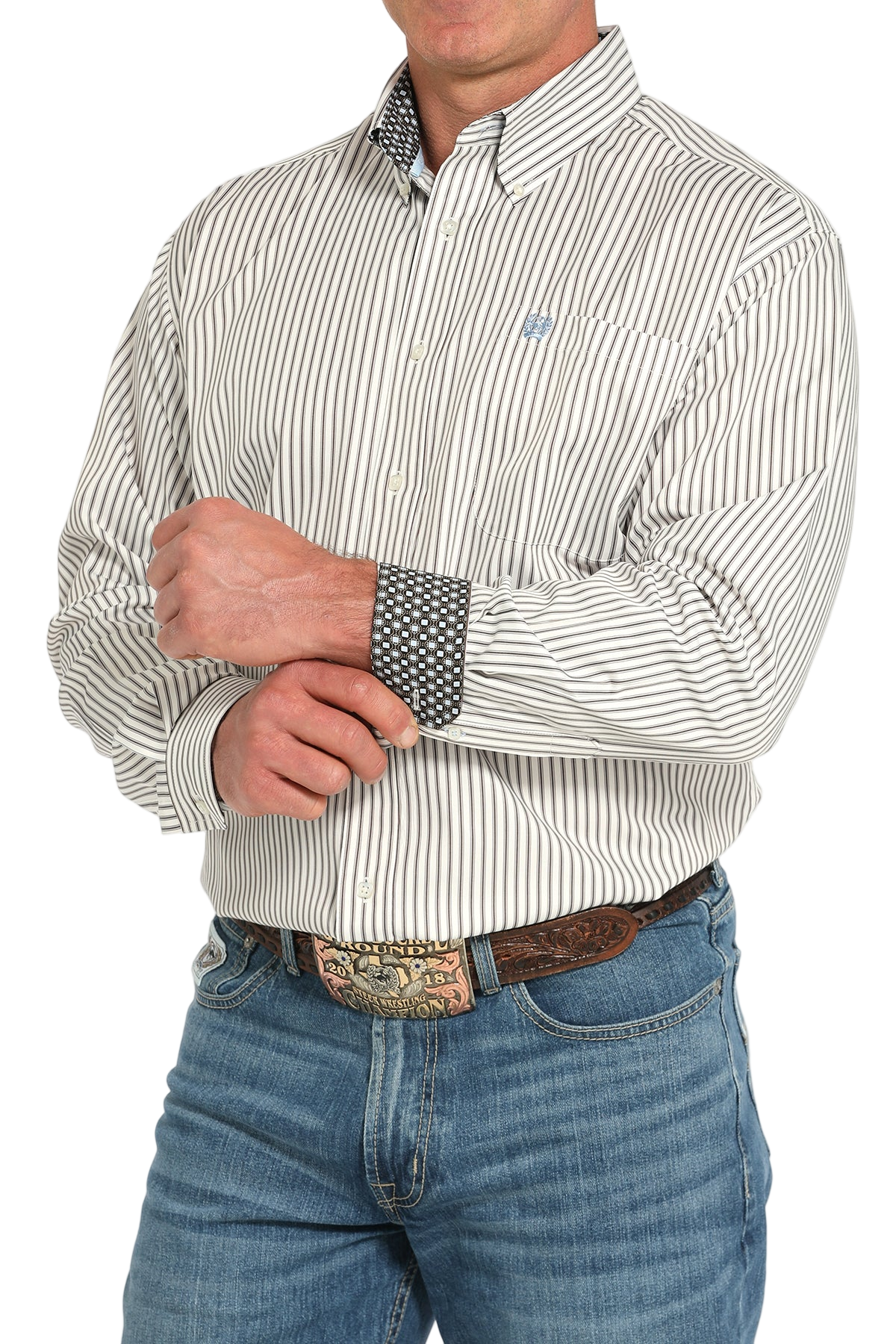 Man wearing a light gray button-up shirt with contrasting cuffs and blue jeans on a white background