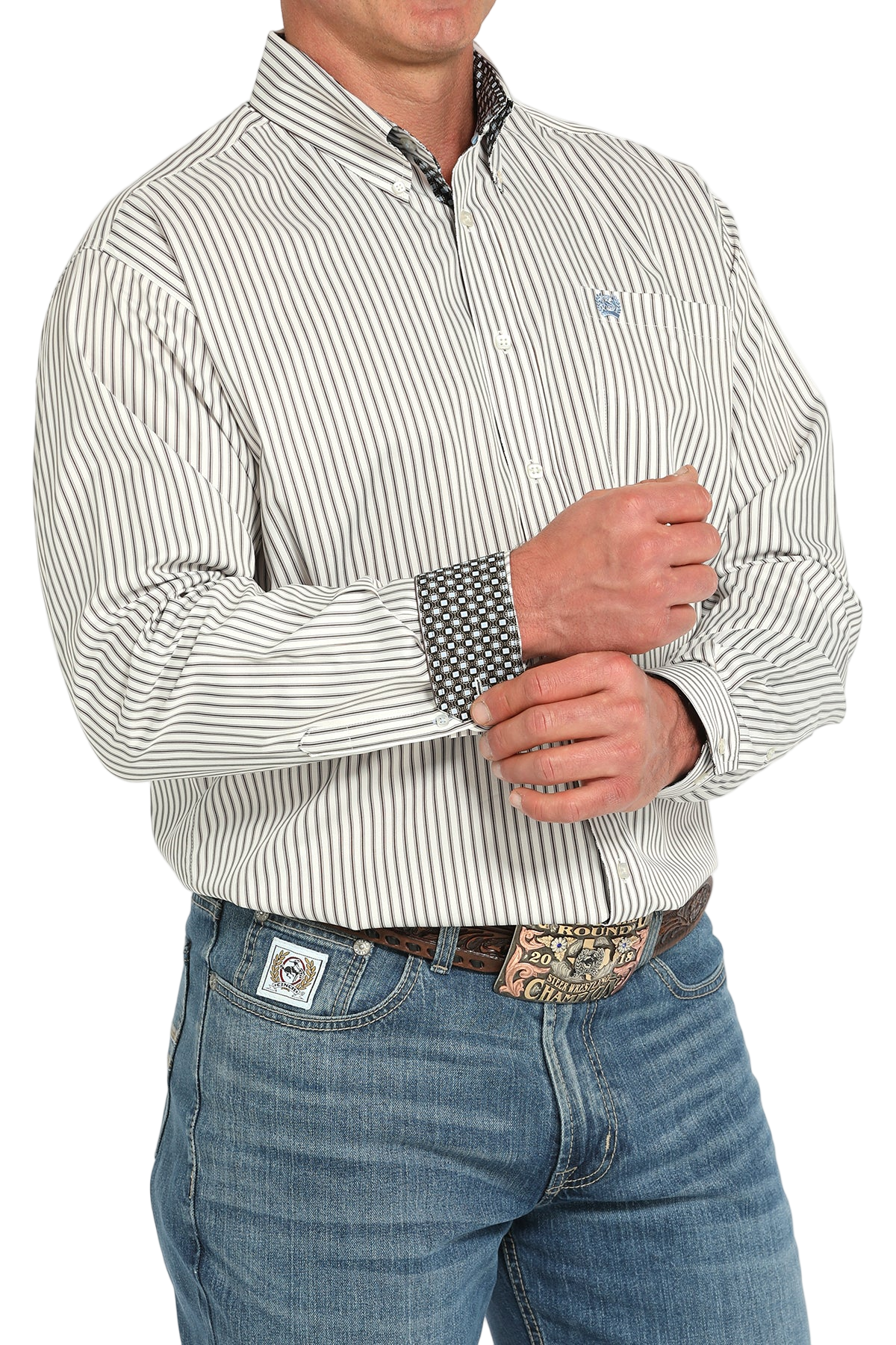 Man wearing a light gray button-up shirt with contrasting cuffs and blue jeans on a white background