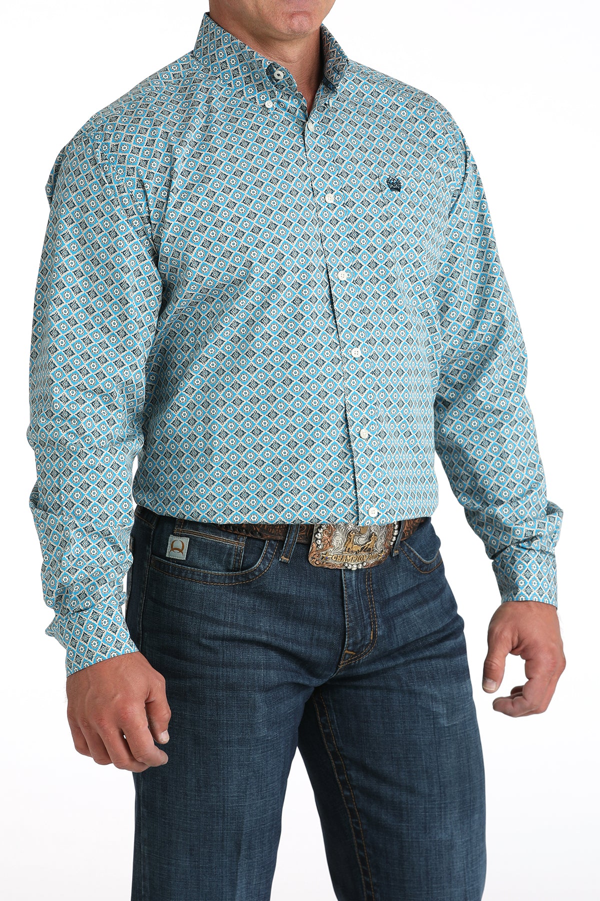 Man wearing a patterned teal shirt and jeans on a white background
