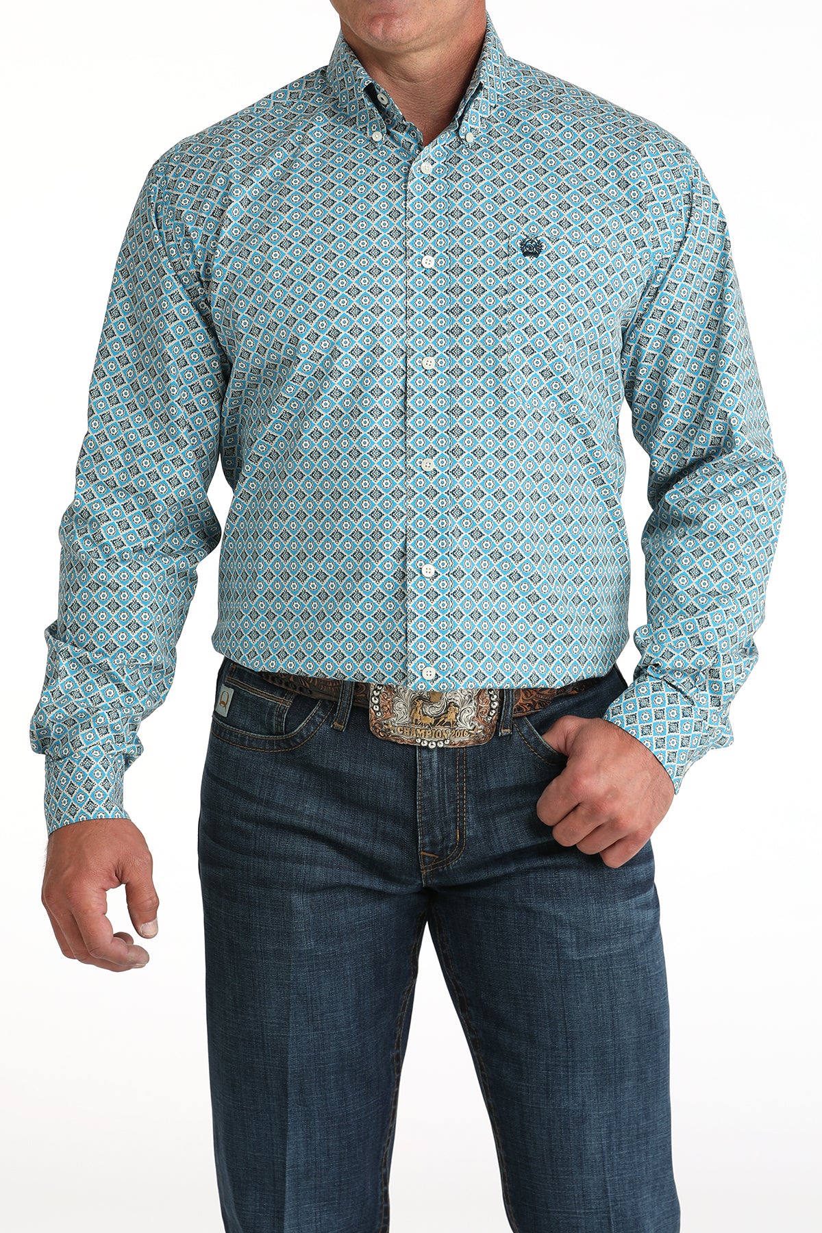 Man wearing a patterned teal shirt and jeans on a white background