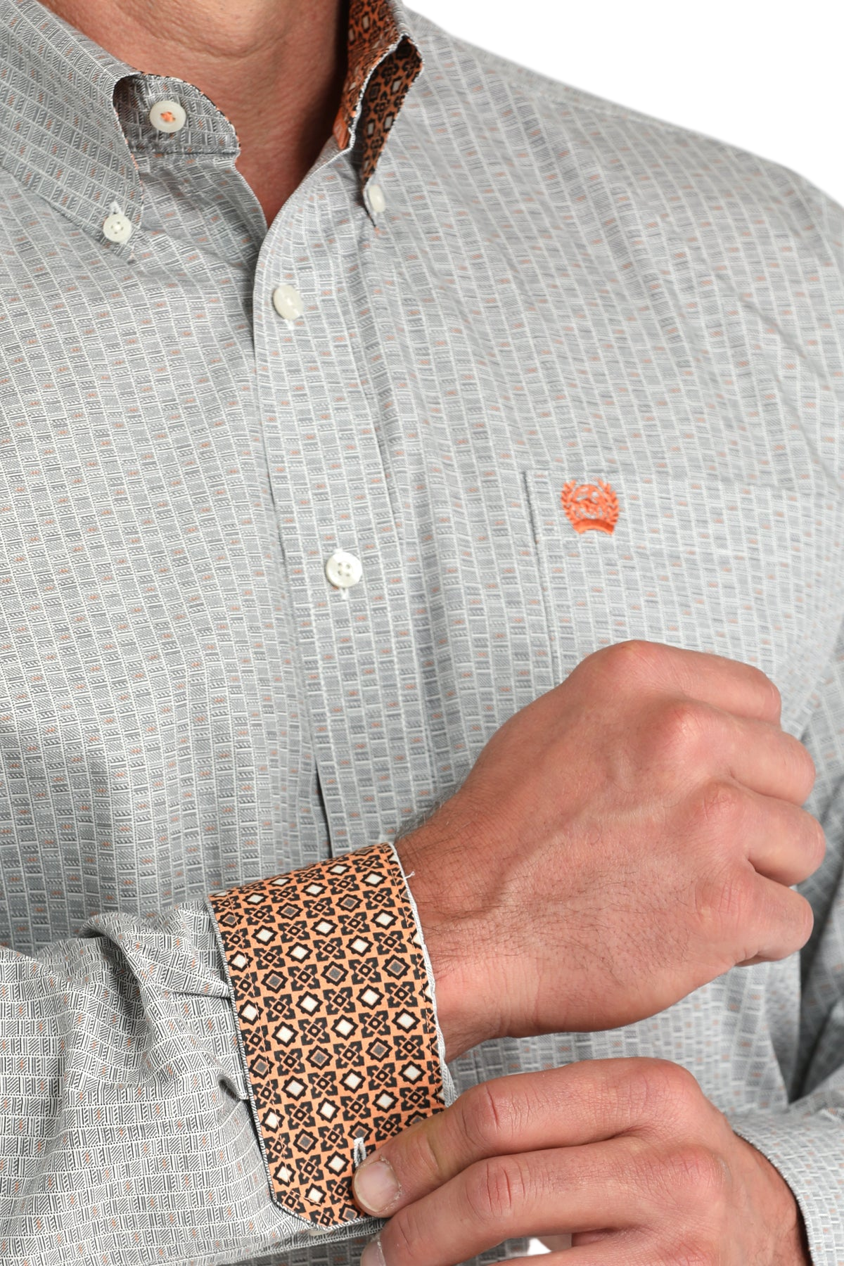 Close-up of a man wearing a patterned gray long sleeve button-down shirt with contrasting cuffs on a transparent background
