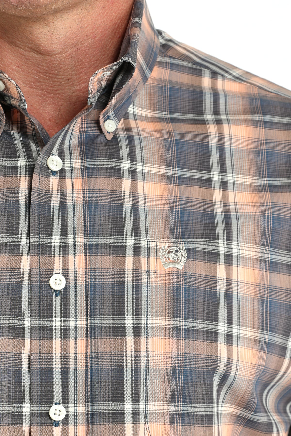 Close-up of a plaid shirt with a visible brand logo on a white background
