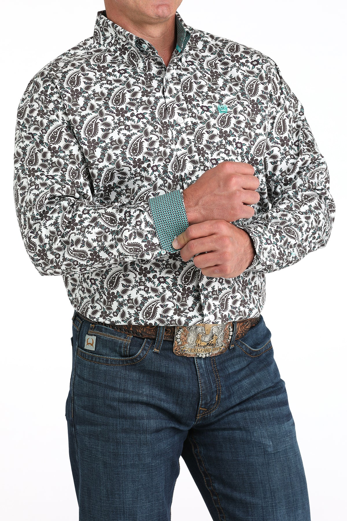 Man wearing a patterned shirt and jeans with a belt buckle on a white background
