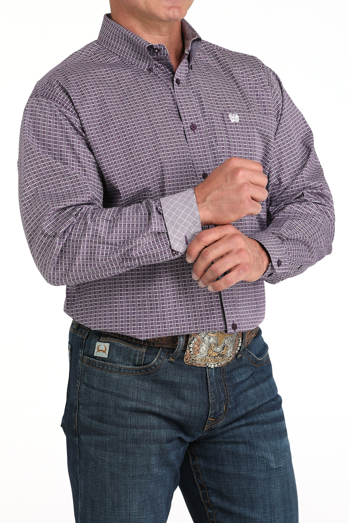 Man wearing a purple long sleeve button-down shirt with a contrasting cuff detail, paired with jeans and a belt