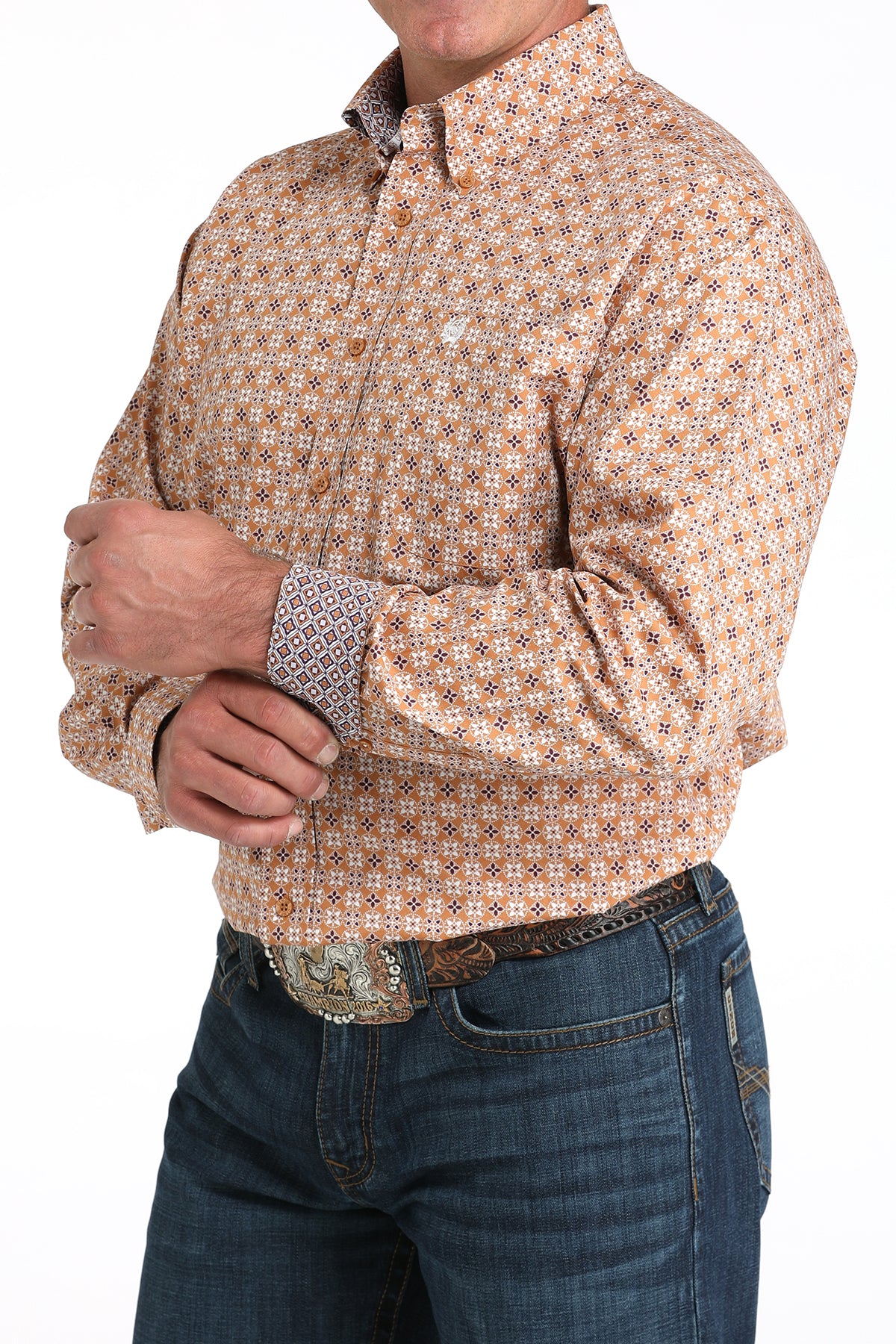 Man wearing a long sleeve button-down shirt that is brown and has a pattern, as well as contrasting cuffs, paired with jeans and a belt