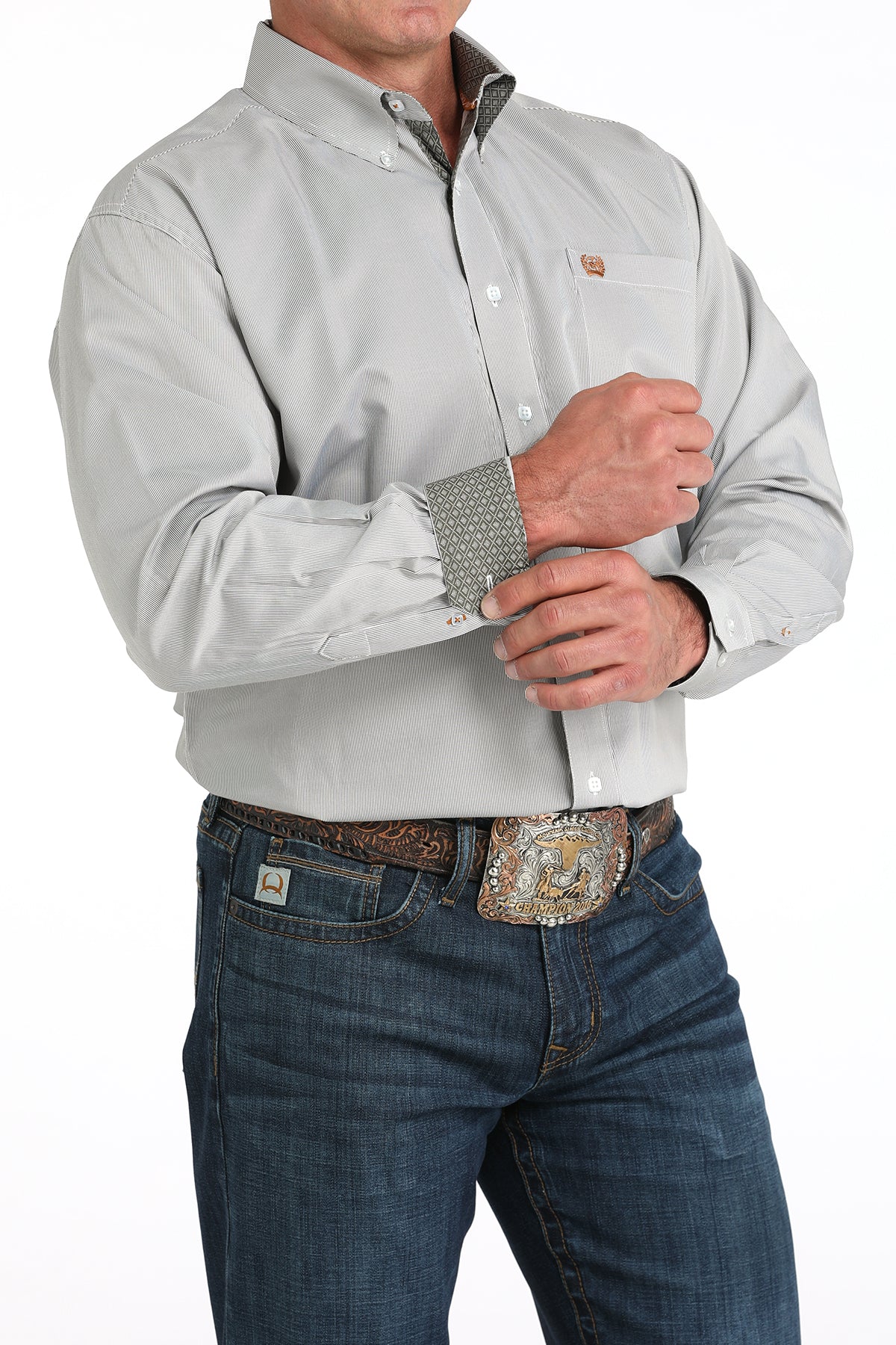Man wearing a white long sleeve button-down with contrasting cuff details, paired with jeans and a belt