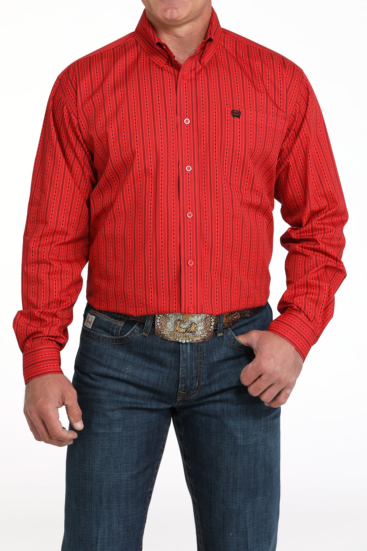 A man wearing a red striped button-up shirt, dark jeans, and a large belt buckle, standing against a white background