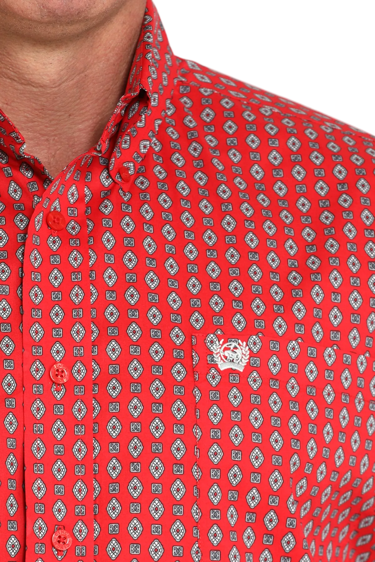 Close-up of a man wearing a red patterned button-up shirt with a small white emblem on the chest, displayed against a transparent background