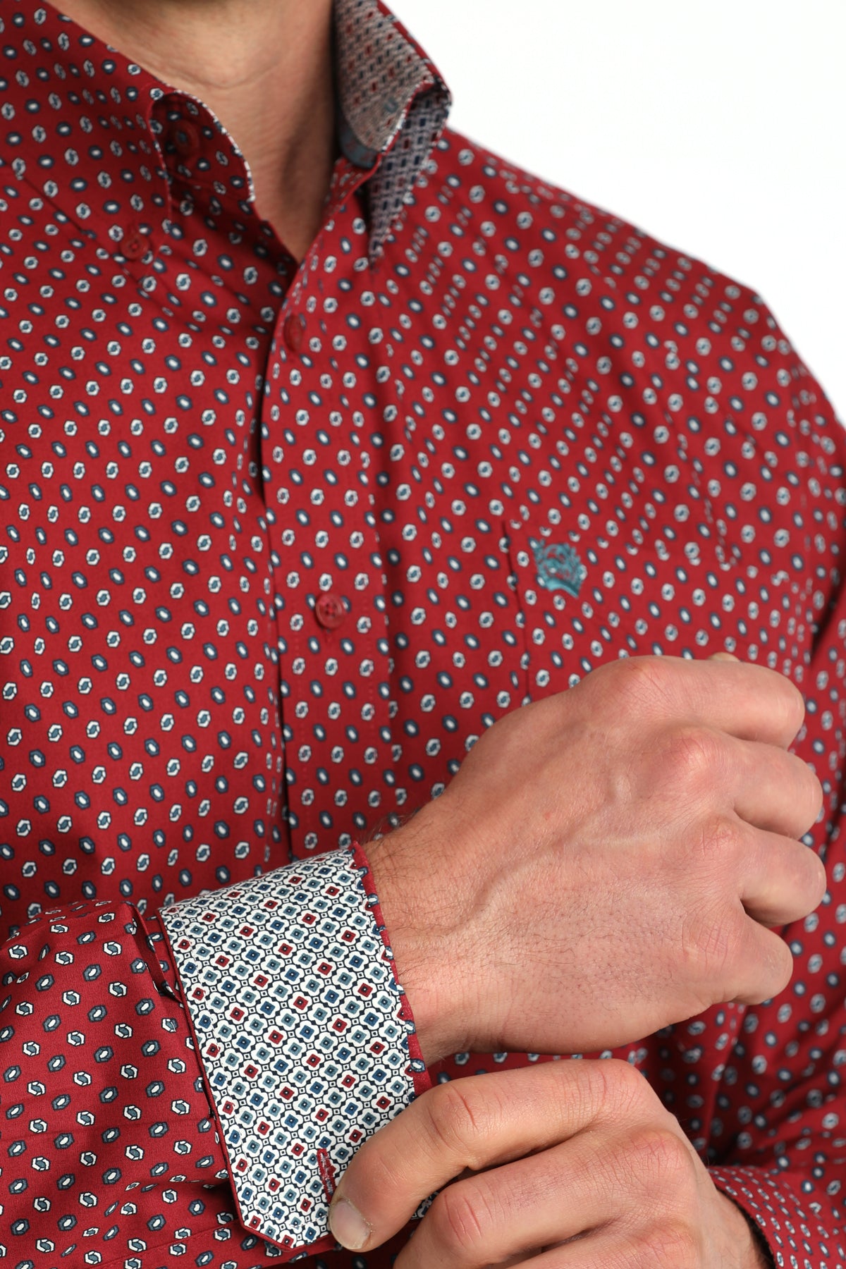 Red patterned shirt with a close-up of a hand adjusting the cuff on a white background