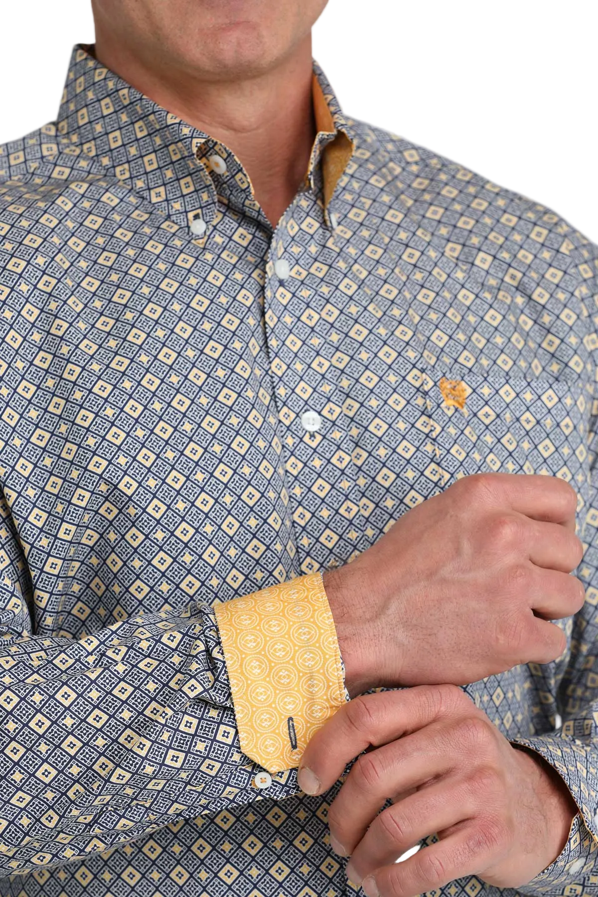 Close-up of a person wearing a patterned shirt with yellow cuffs.