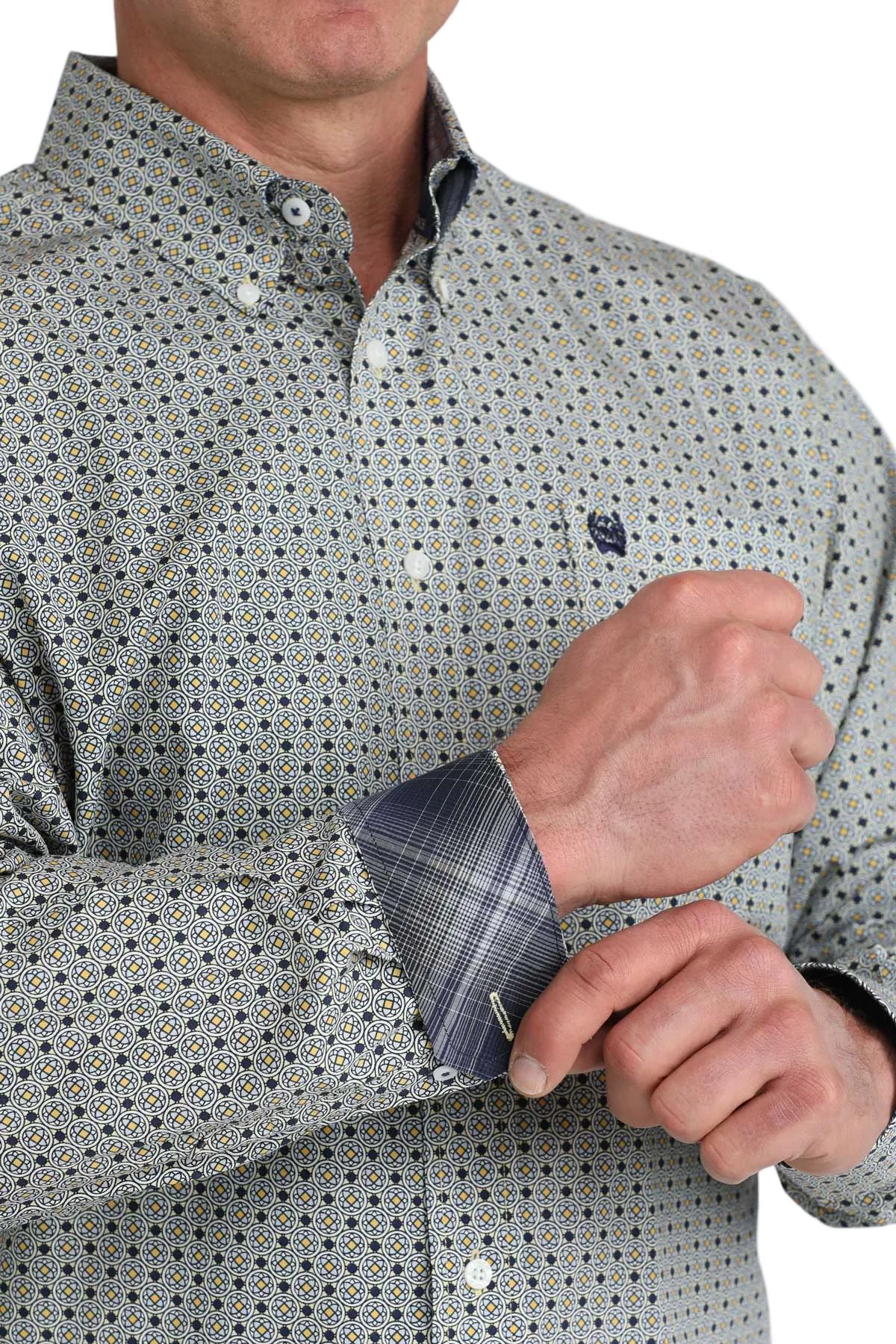 Close-up of a person adjusting the cuff of a patterned shirt with a white background