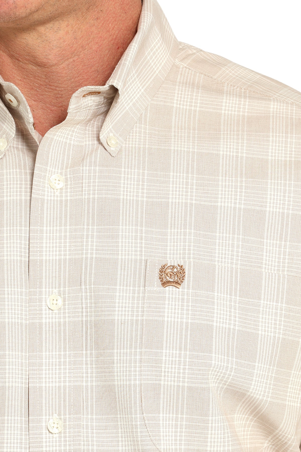 Close-up of a beige checkered shirt with a small logo on the chest.