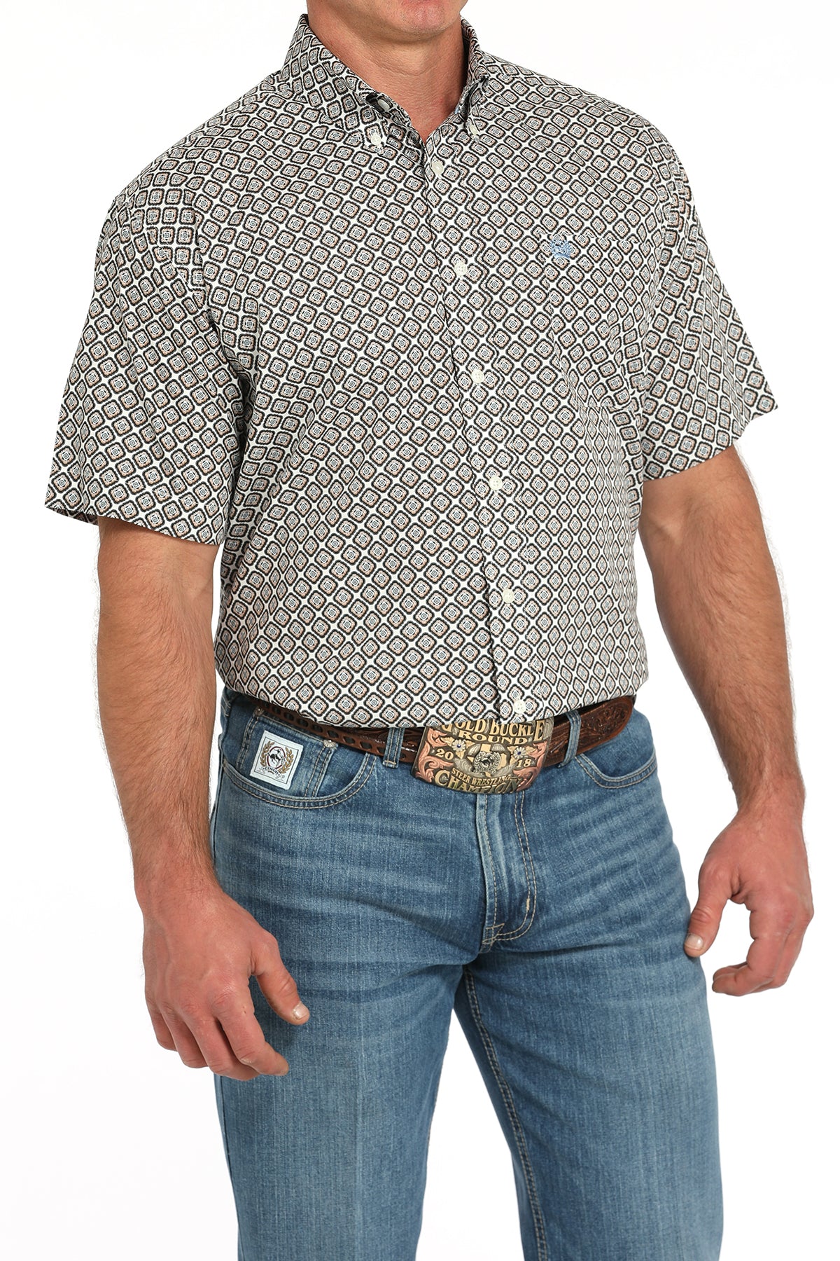 Man wearing a patterned short sleeve button-down with jeans and a belt