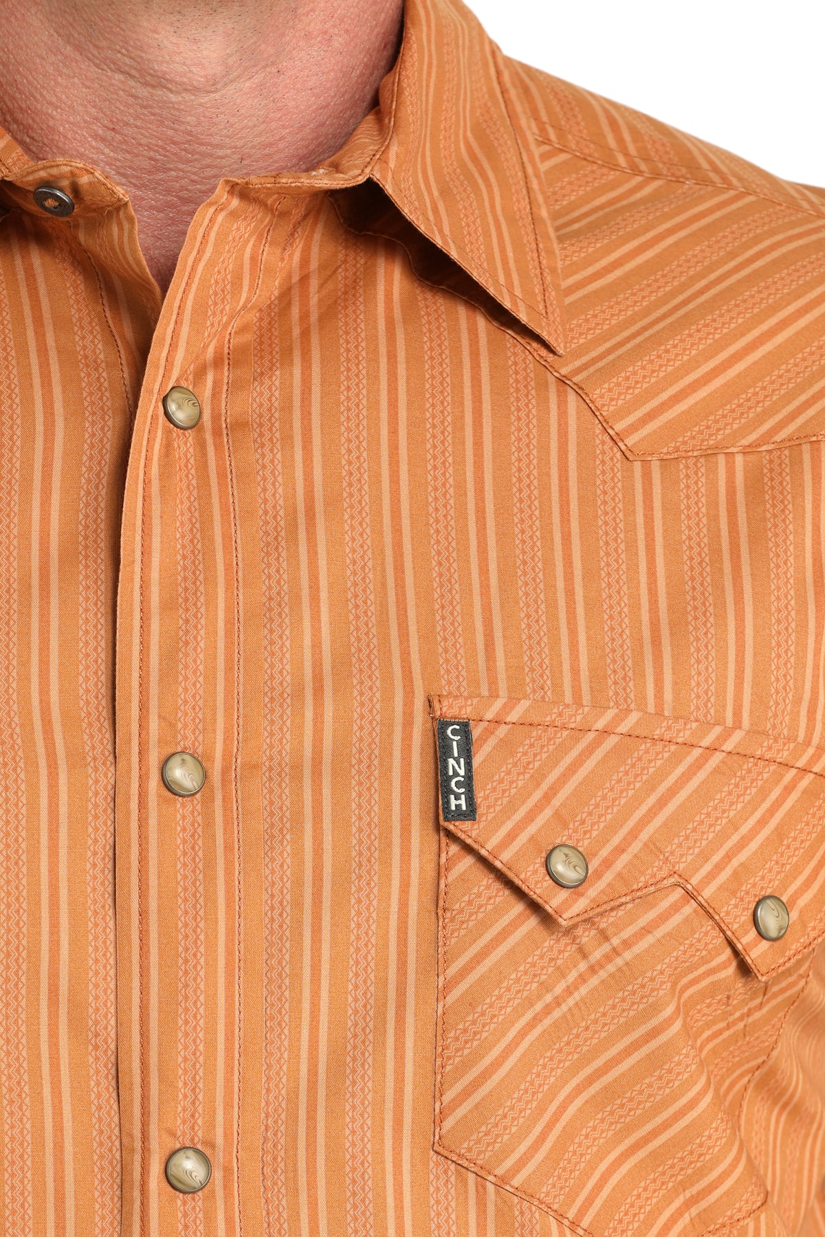Close-up of a brown patterned shirt with a brand logo on a white background