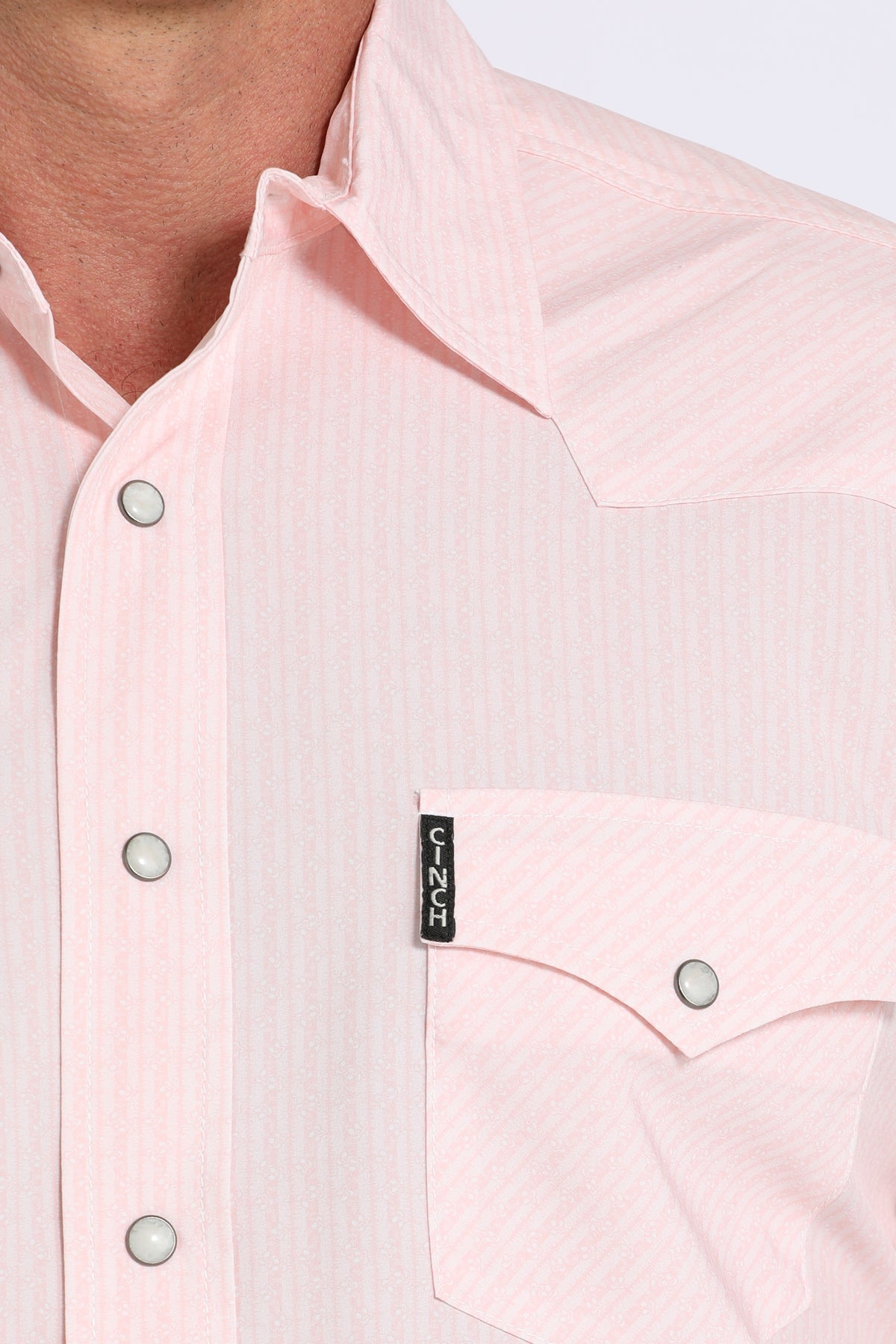 Close-up of a light pink shirt with a brand label on a white background