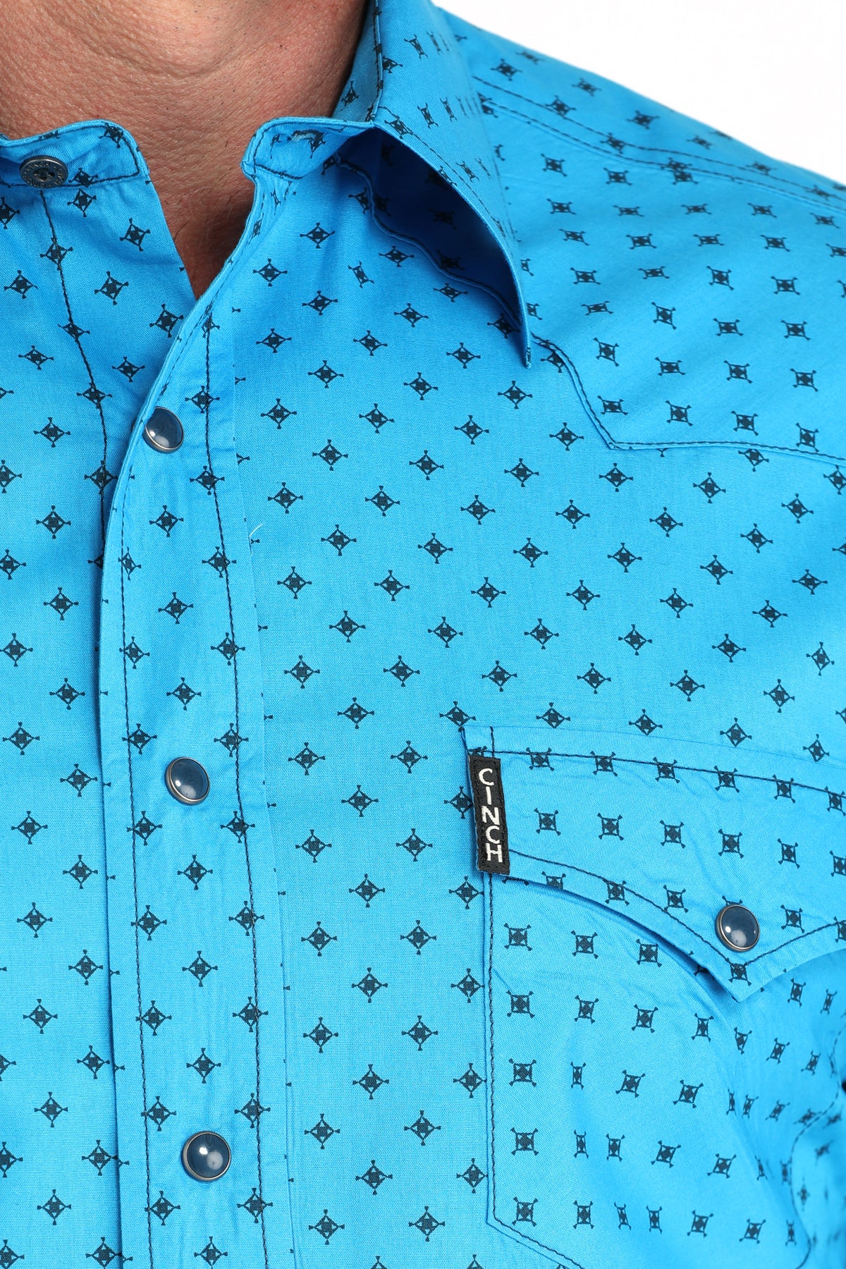 Close-up of a blue shirt with black pattern and brand logo.