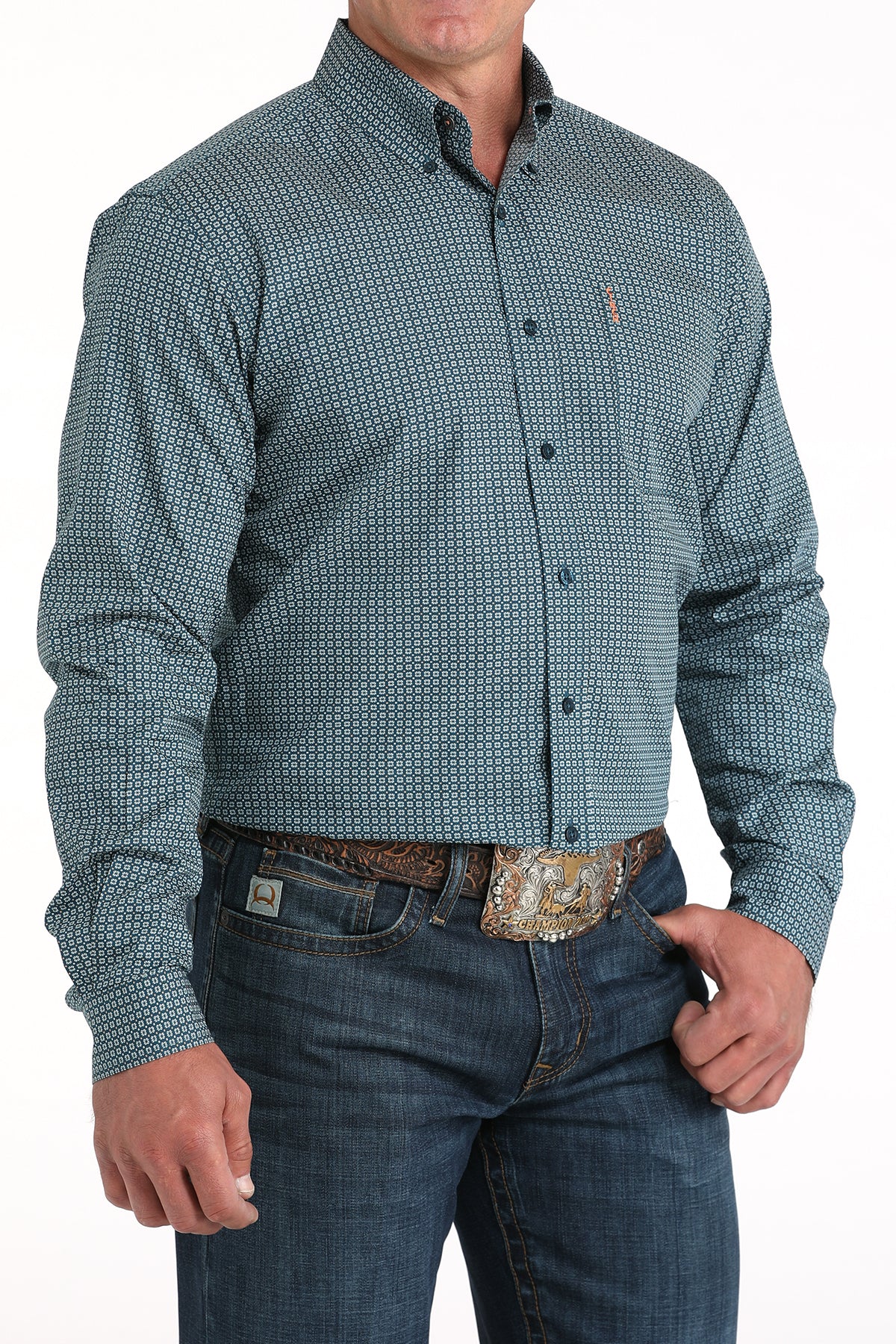 Man wearing a patterned blue shirt and jeans with a belt buckle.
