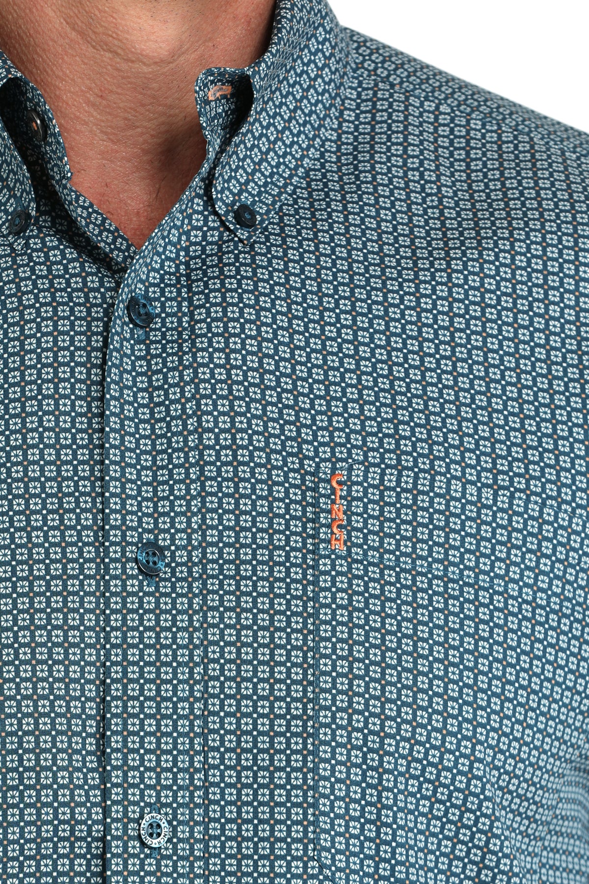 Close-up of a patterned shirt with a brand logo on a plain background