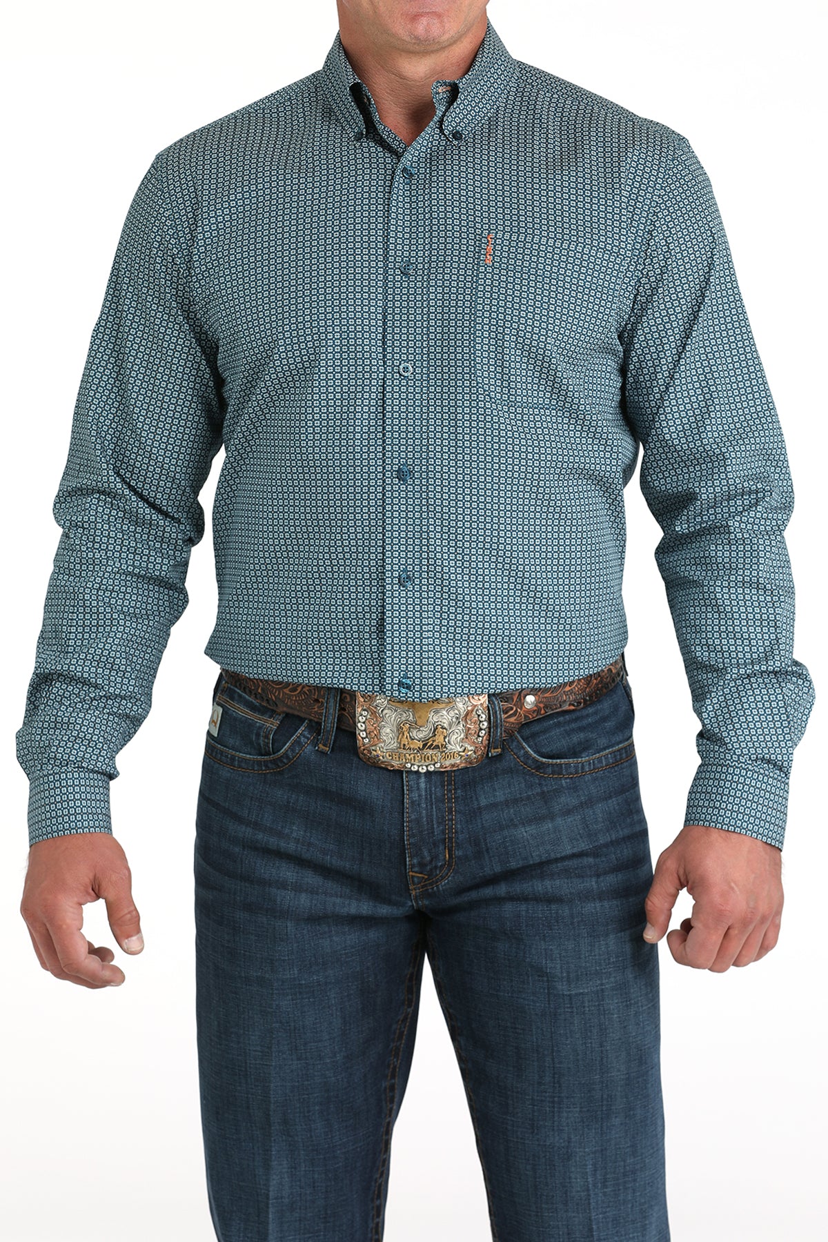 Man wearing a patterned teal shirt and jeans with a belt and buckle on a white background