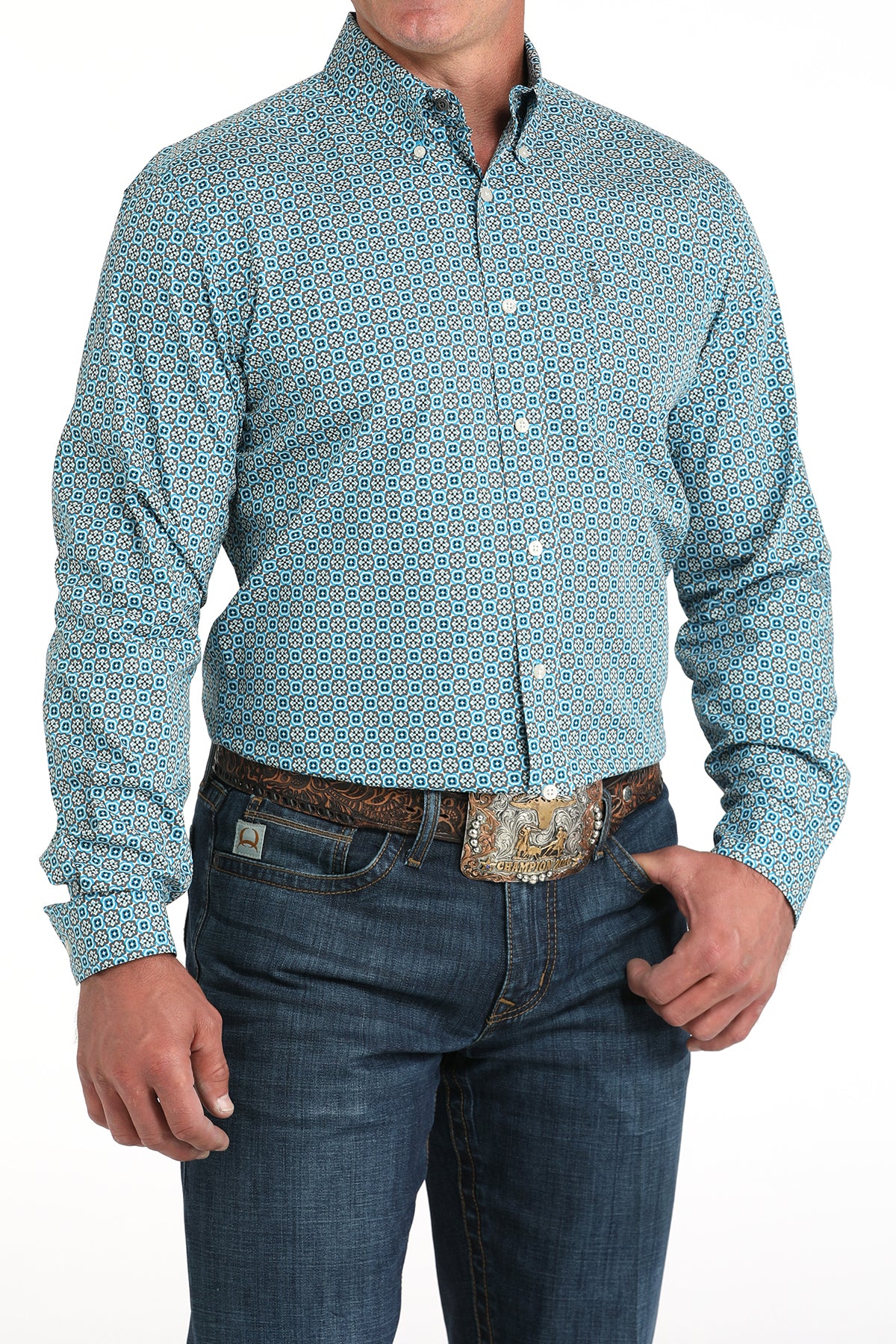 Man wearing a patterned teal shirt and jeans on a white background