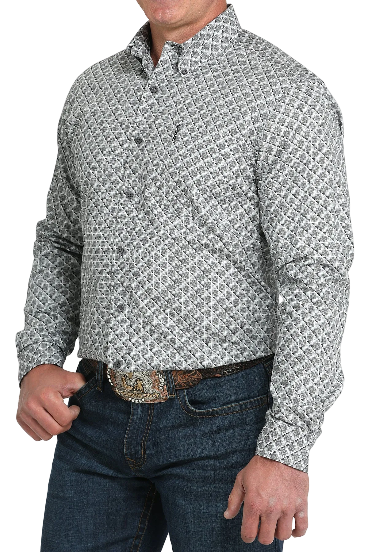 A man wearing a light gray patterned button-up shirt, dark jeans, and a large belt buckle, standing against a white background