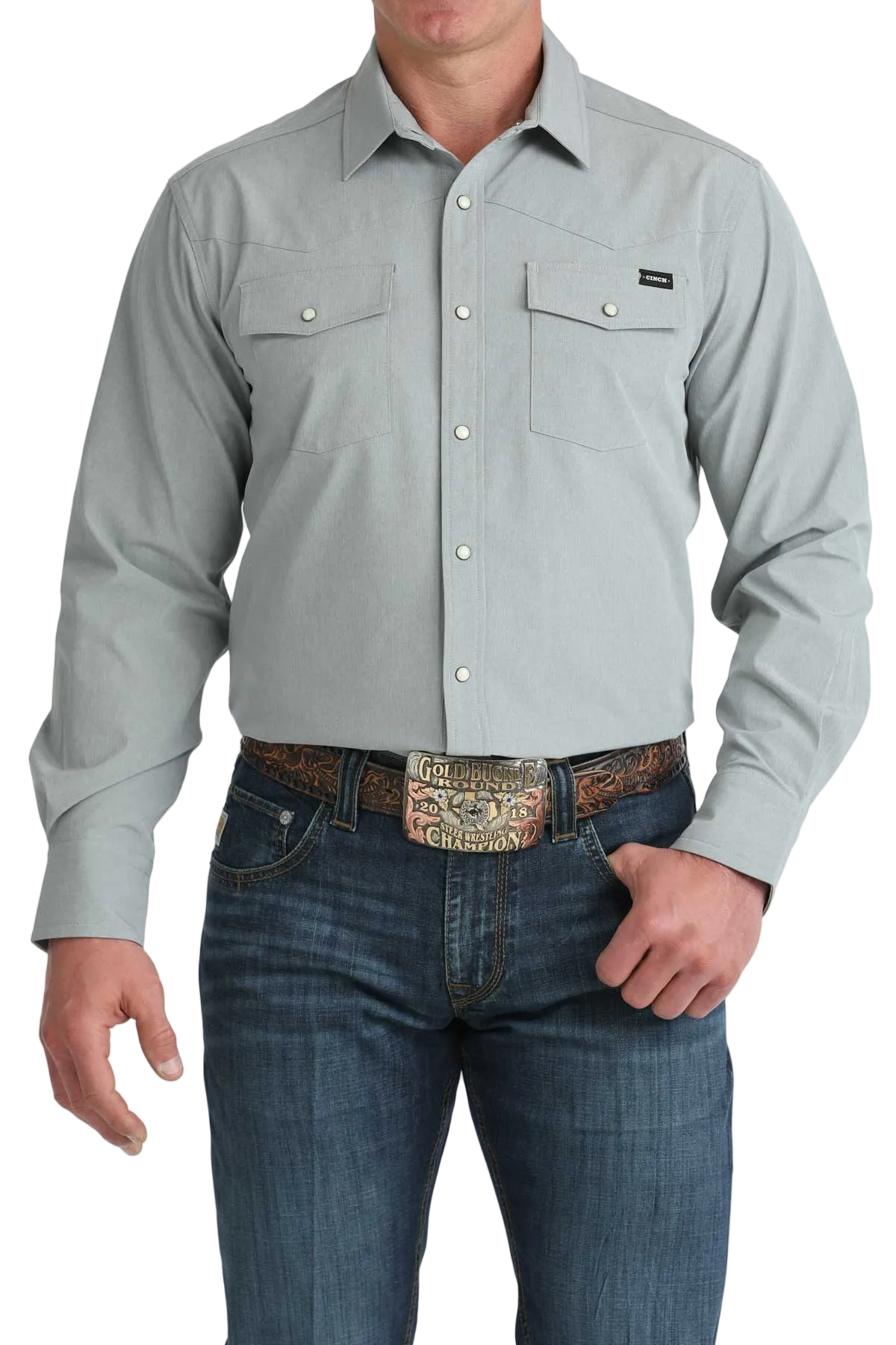 Man wearing a gray button-up shirt and blue jeans with a decorative belt on a white background