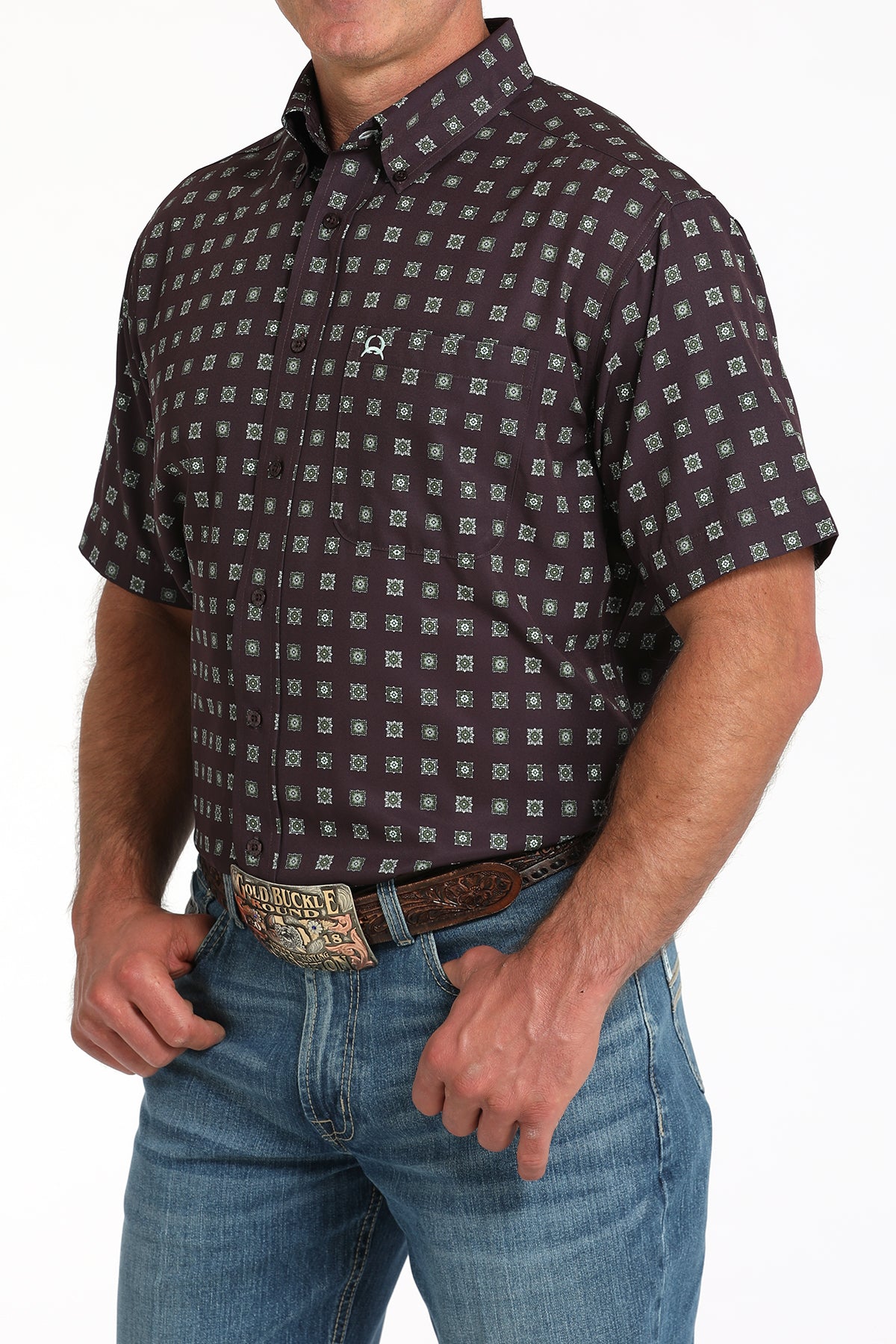 Man wearing a maroon short-sleeve button-down shirt with a geometric print and light blue jeans on a white background