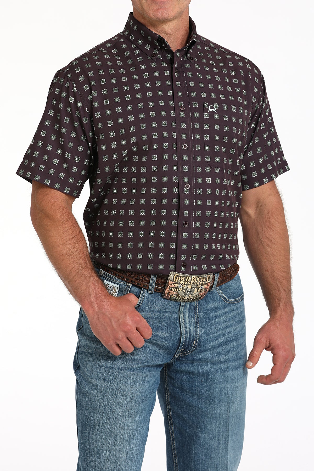 Man wearing a maroon short-sleeve button-down shirt with a geometric print and light blue jeans on a white background