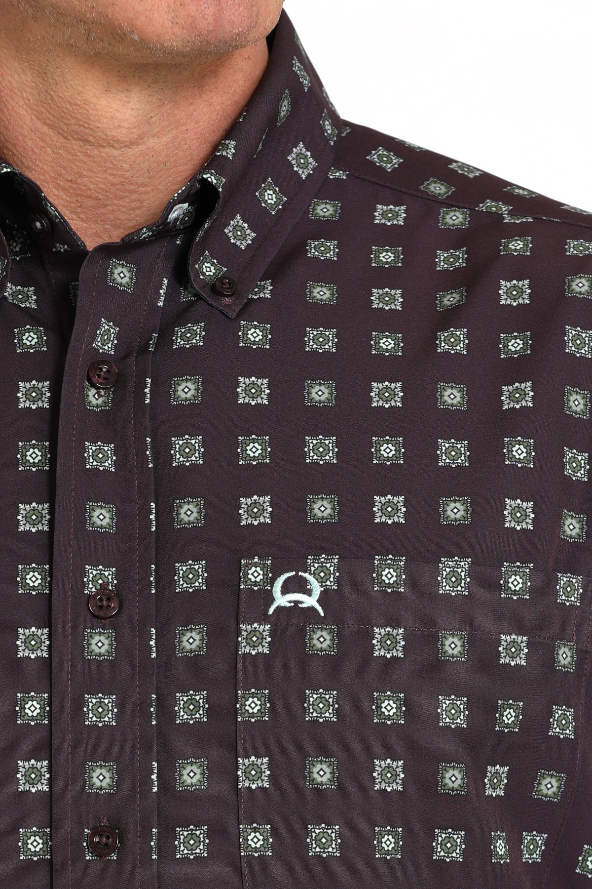 Close-up view of a maroon short-sleeve button-down shirt with a geometric print and the CINCH symbol on a white background