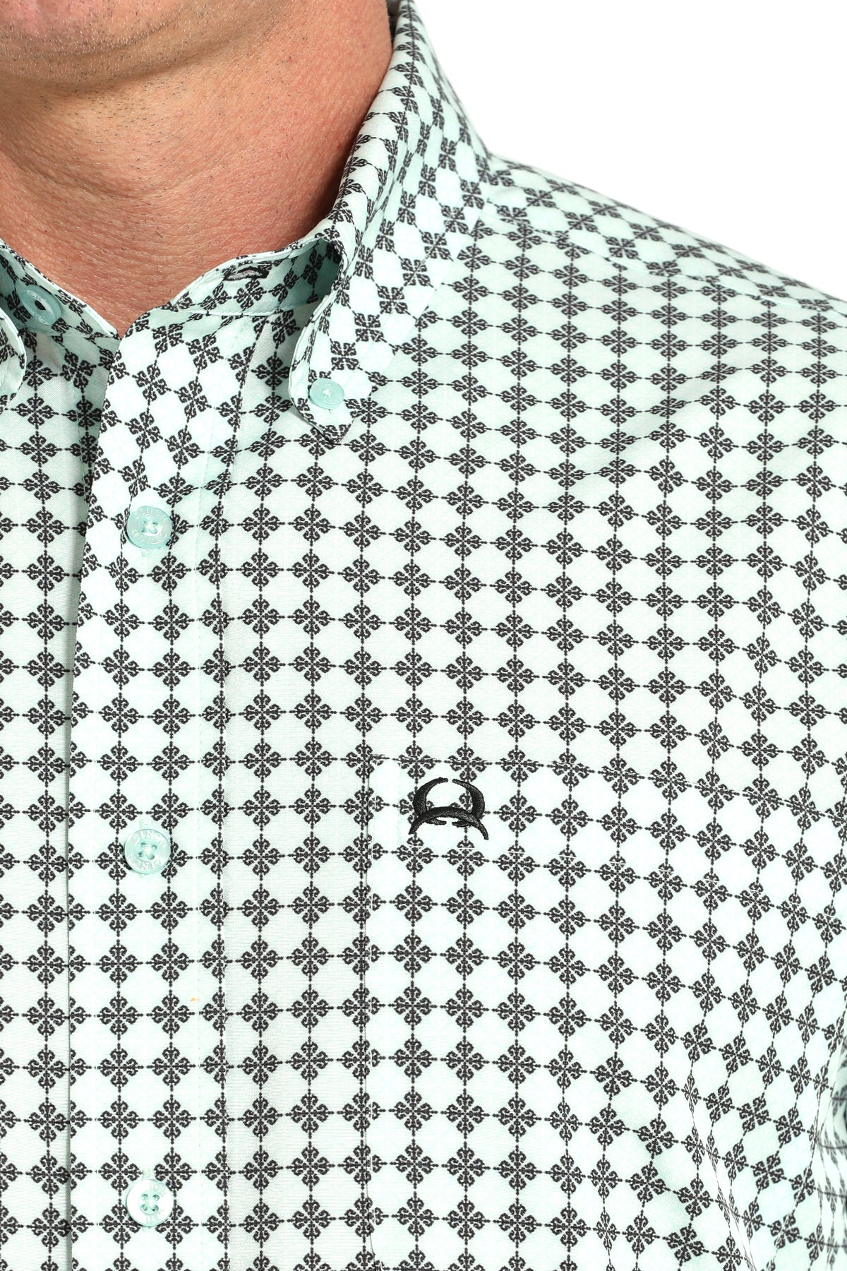 Close-up of a patterned shirt with a small logo on a white background
